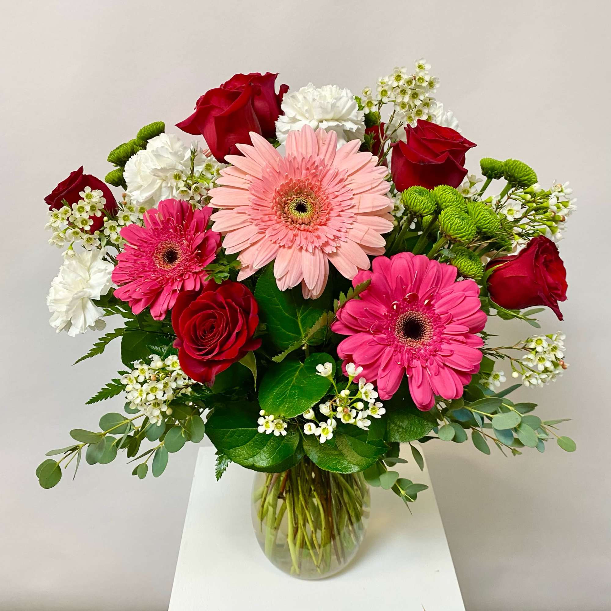 Bouquet of pink gerbera daisies and red roses in a glass vase
