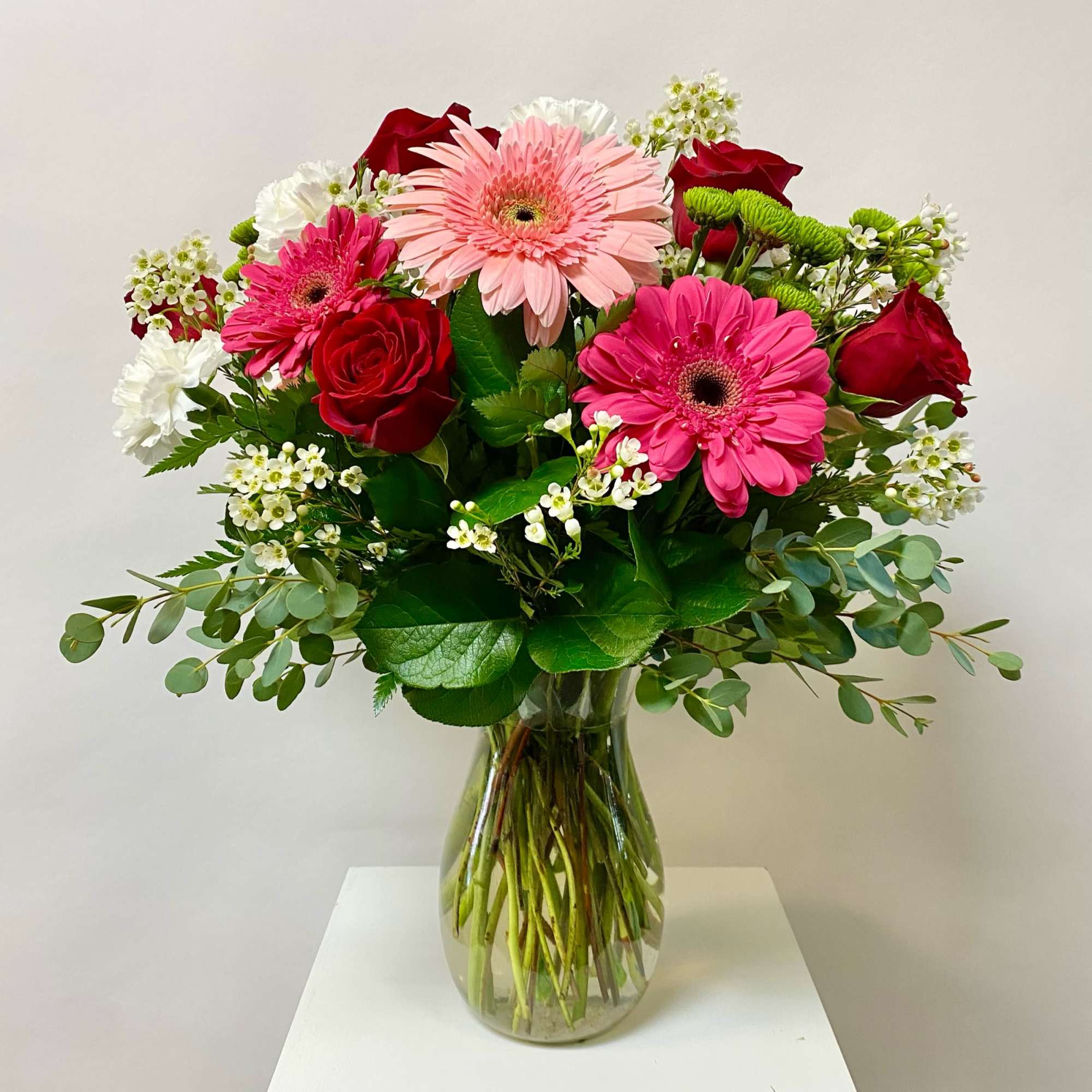 Bouquet of pink gerbera daisies and red roses in a glass vase