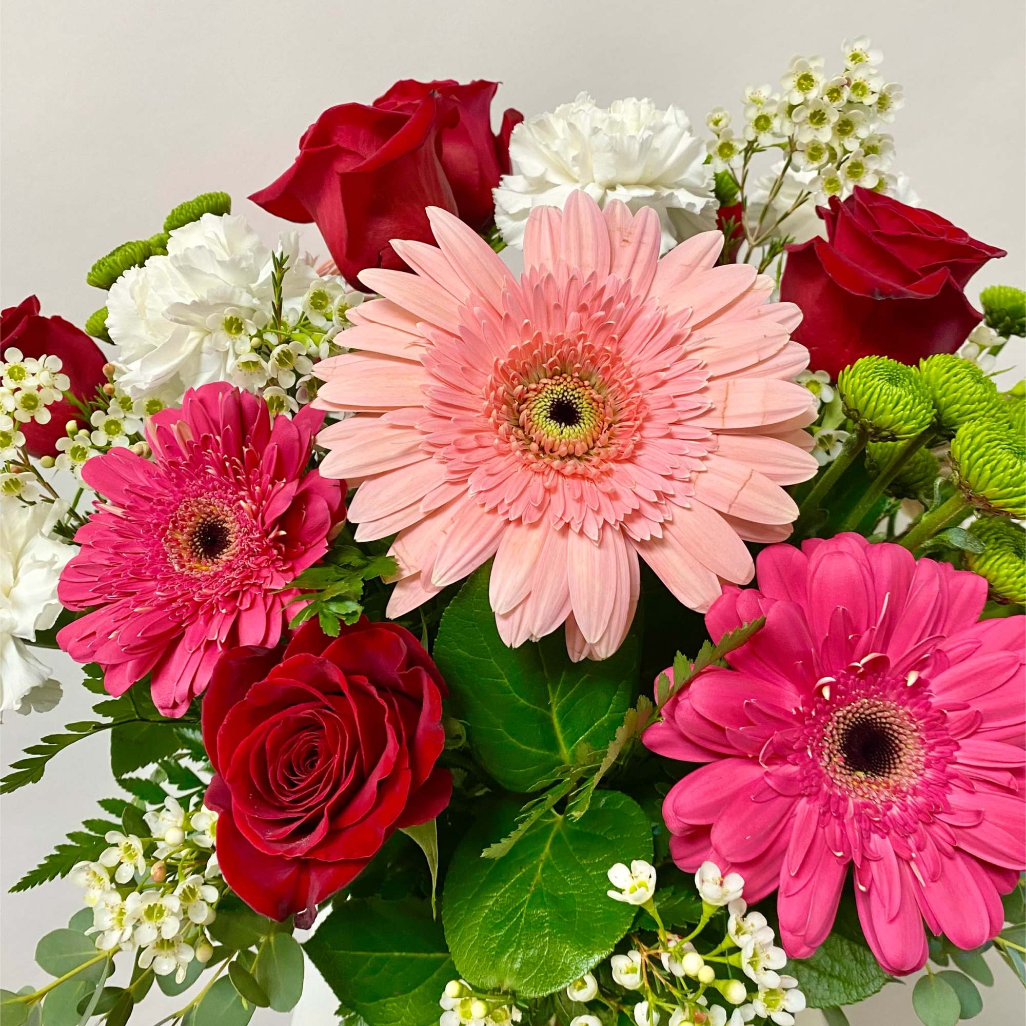 Bouquet of pink gerbera daisies and red roses with white filler flowers
