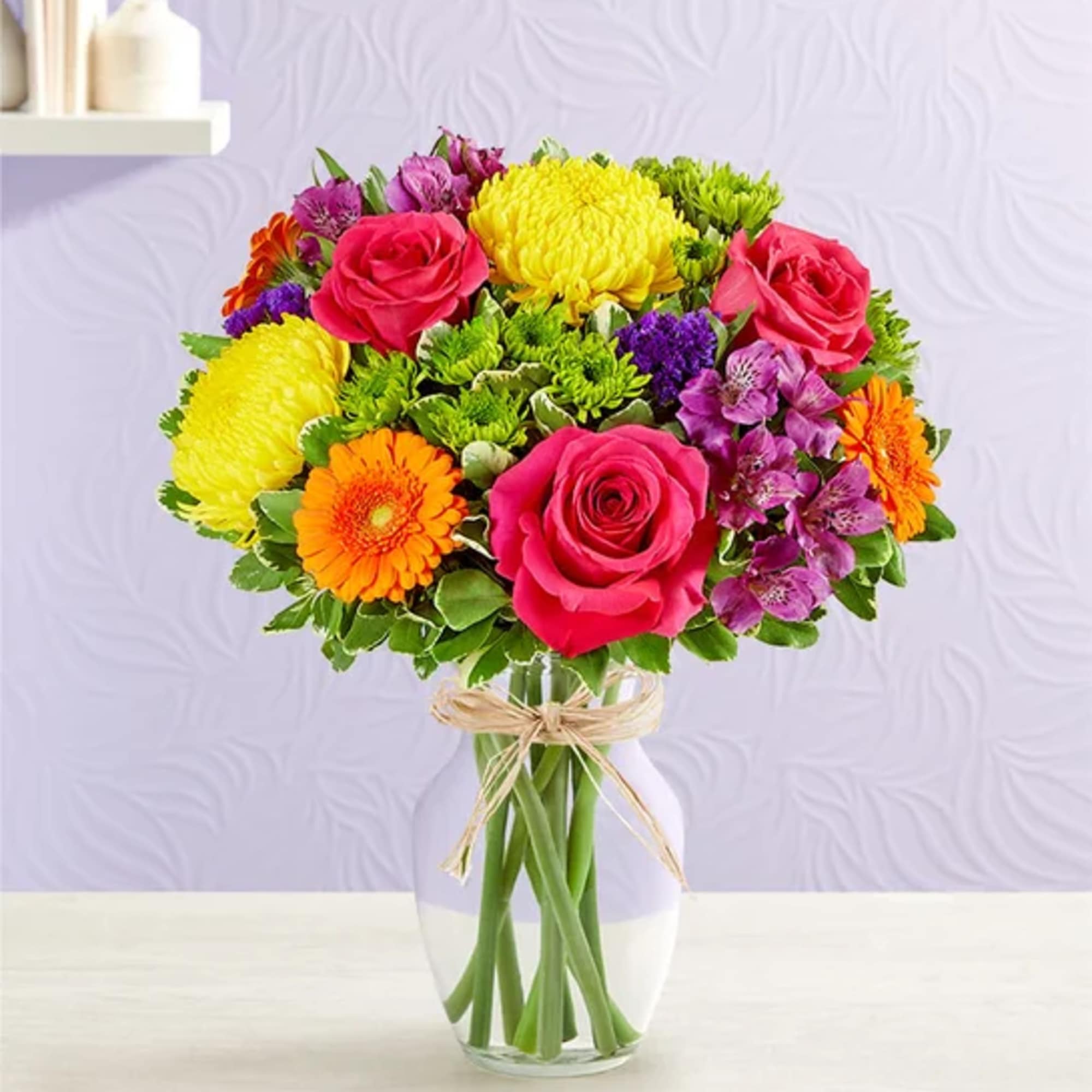 Colorful bouquet of roses, chrysanthemums, gerbera daisies, and alstroemeria in a glass vase
