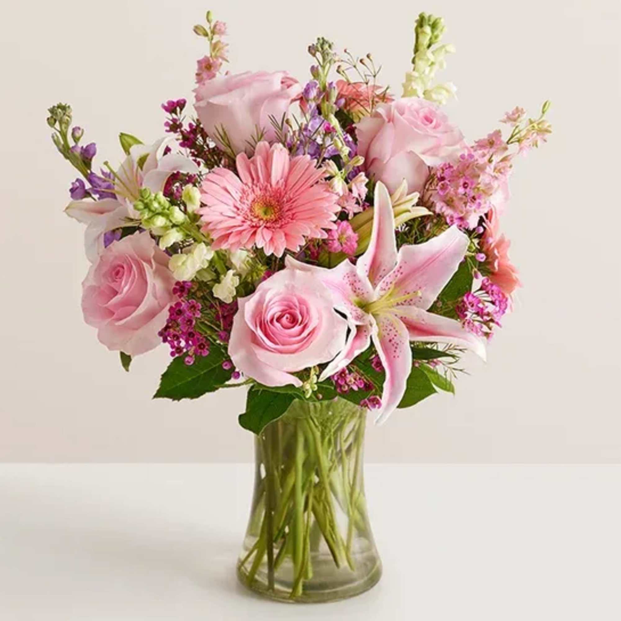 Pink mixed bouquet with roses and lilies in a clear glass vase