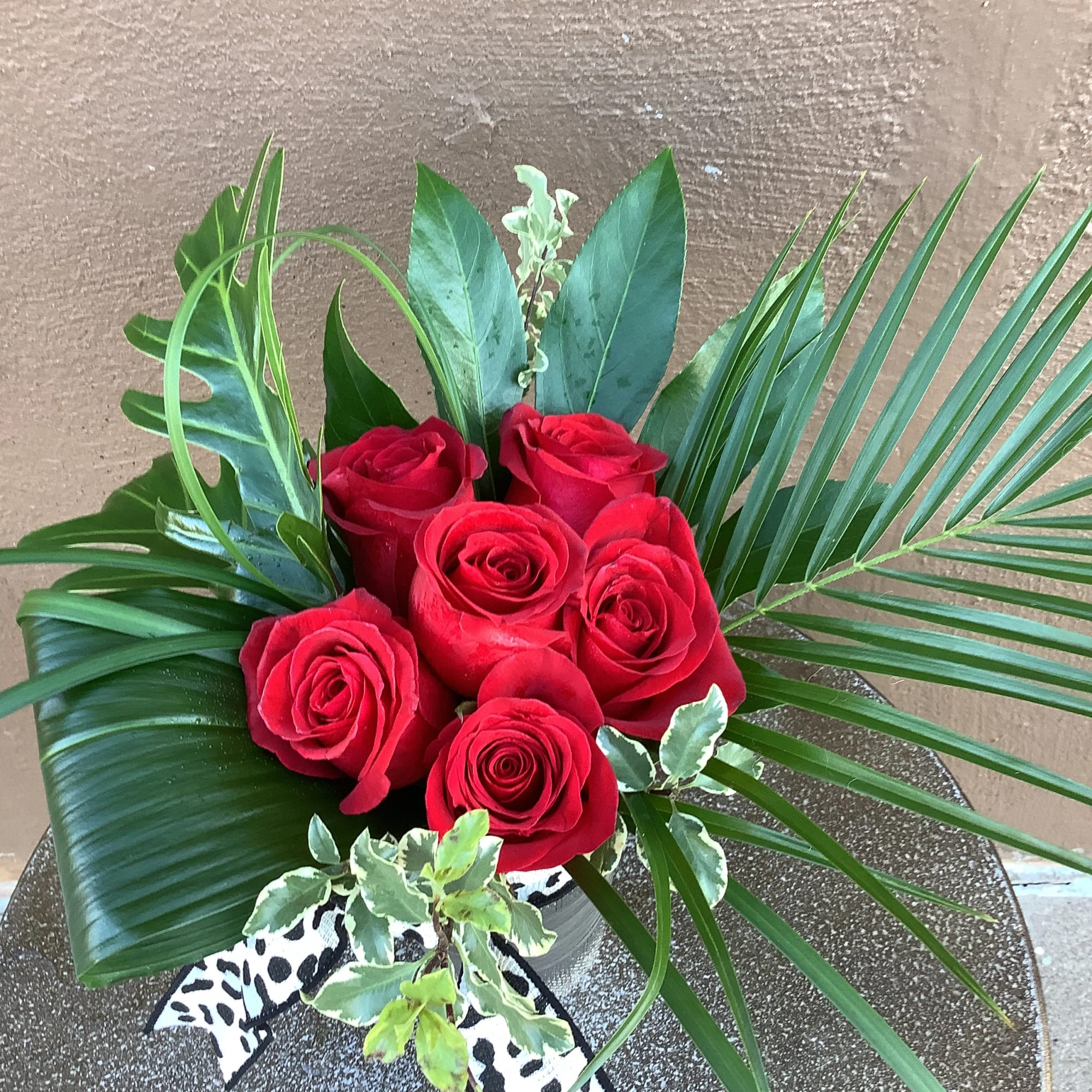 Six beautiful red roses with tropical forges and a black cheetah ribbon