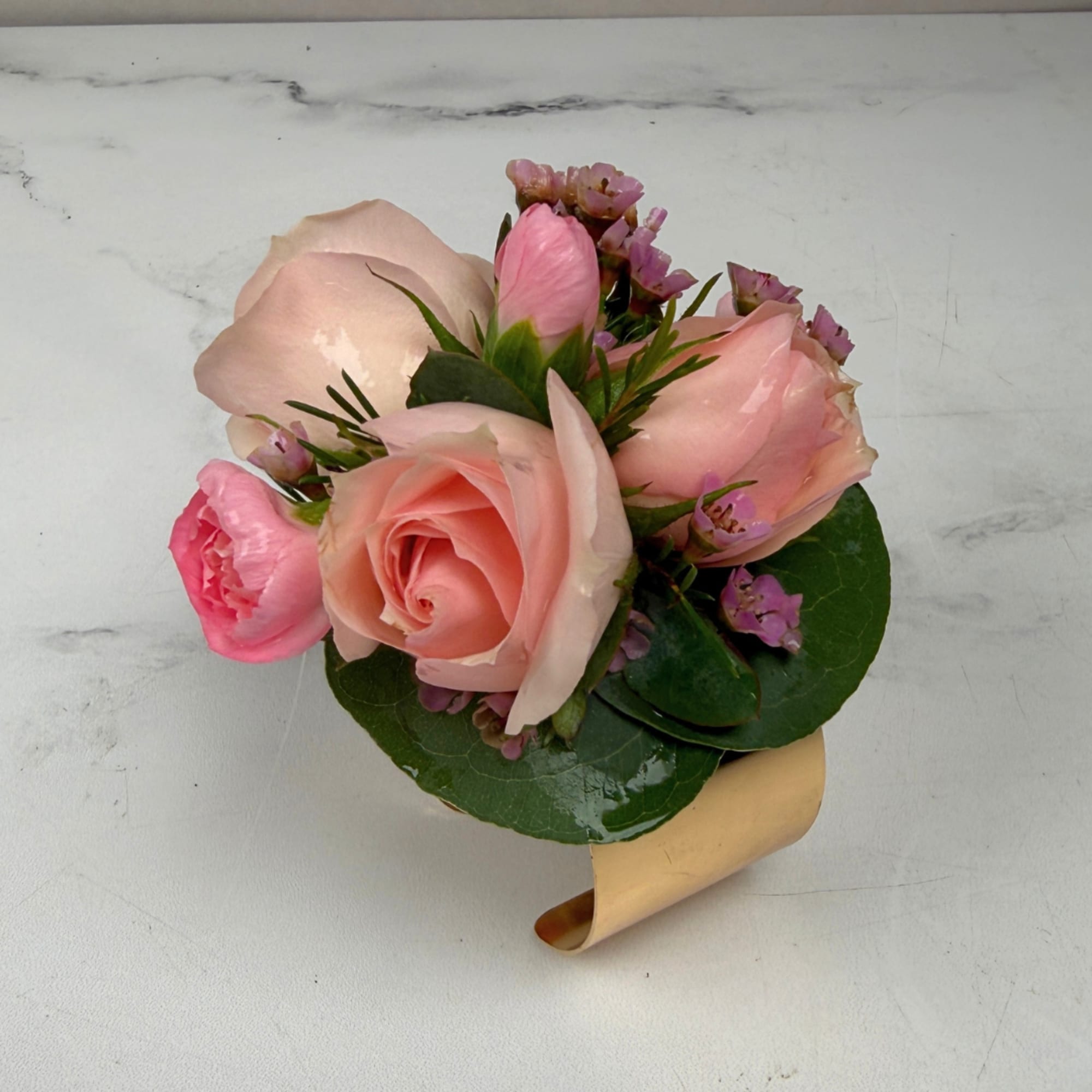 Pale blush roses clustered with pink carnations and tiny pink waxflower fillers