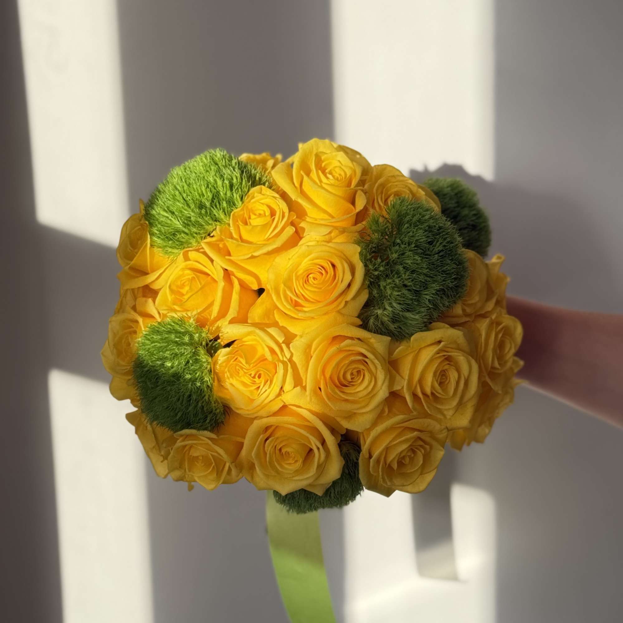 Yellow rose bouquet with green pom-pom accents and a ribbon handle