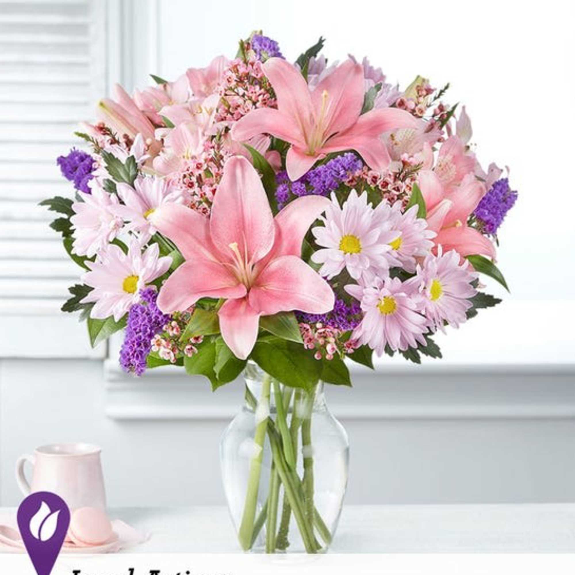 Pink lilies and daisies arranged in a clear glass vase