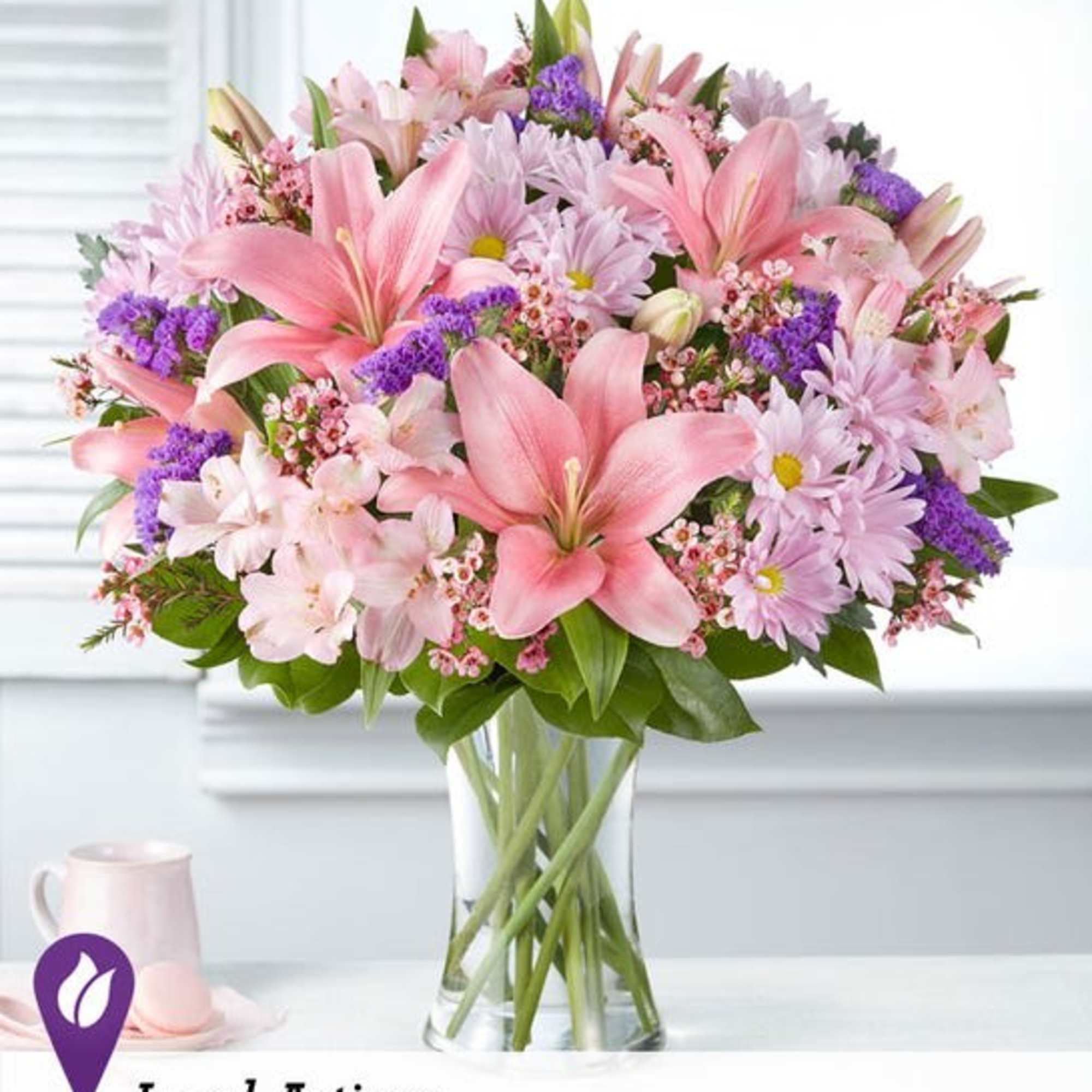 Pink lilies and daisies arranged in a clear glass vase