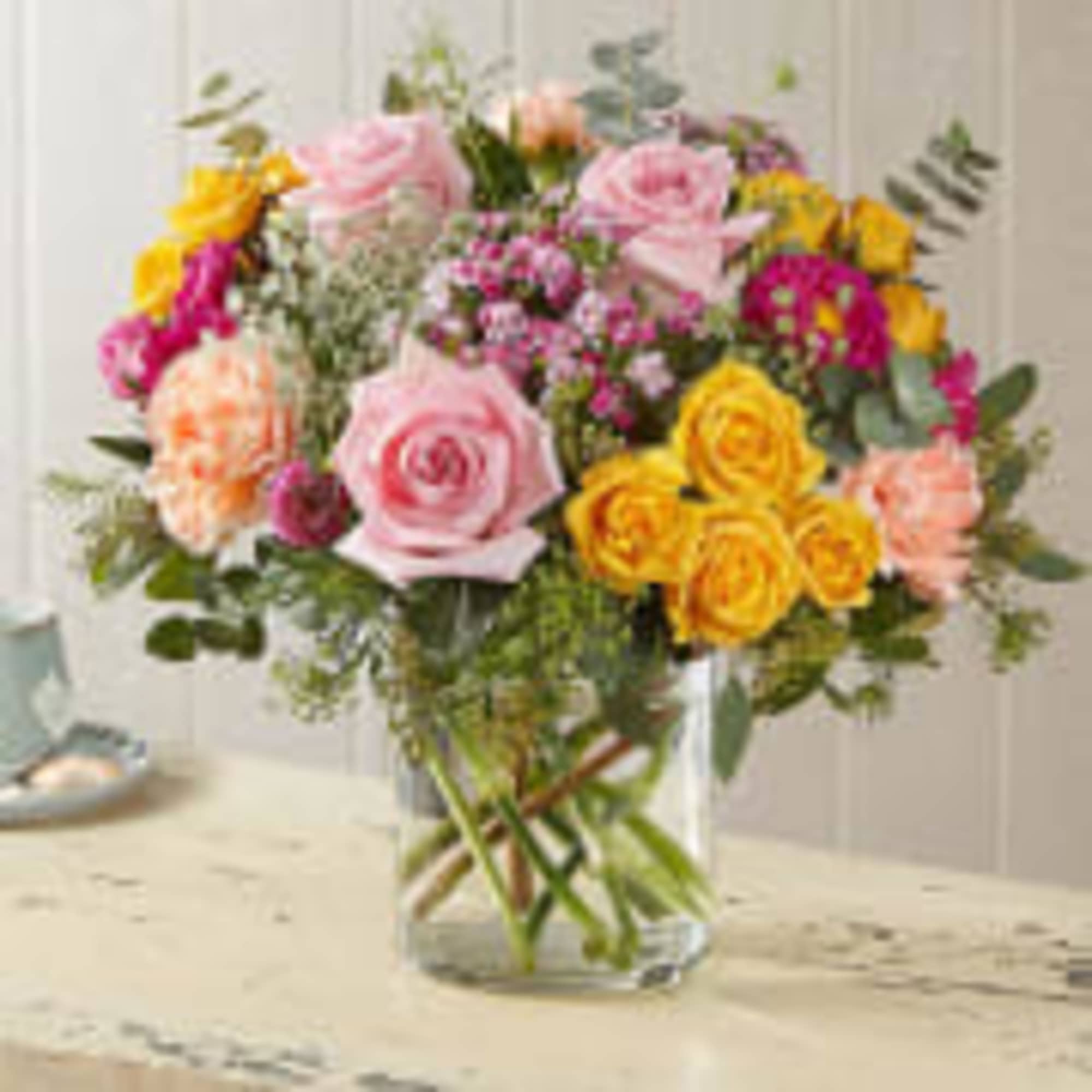 Mixed bouquet of pink and yellow roses in a clear glass vase