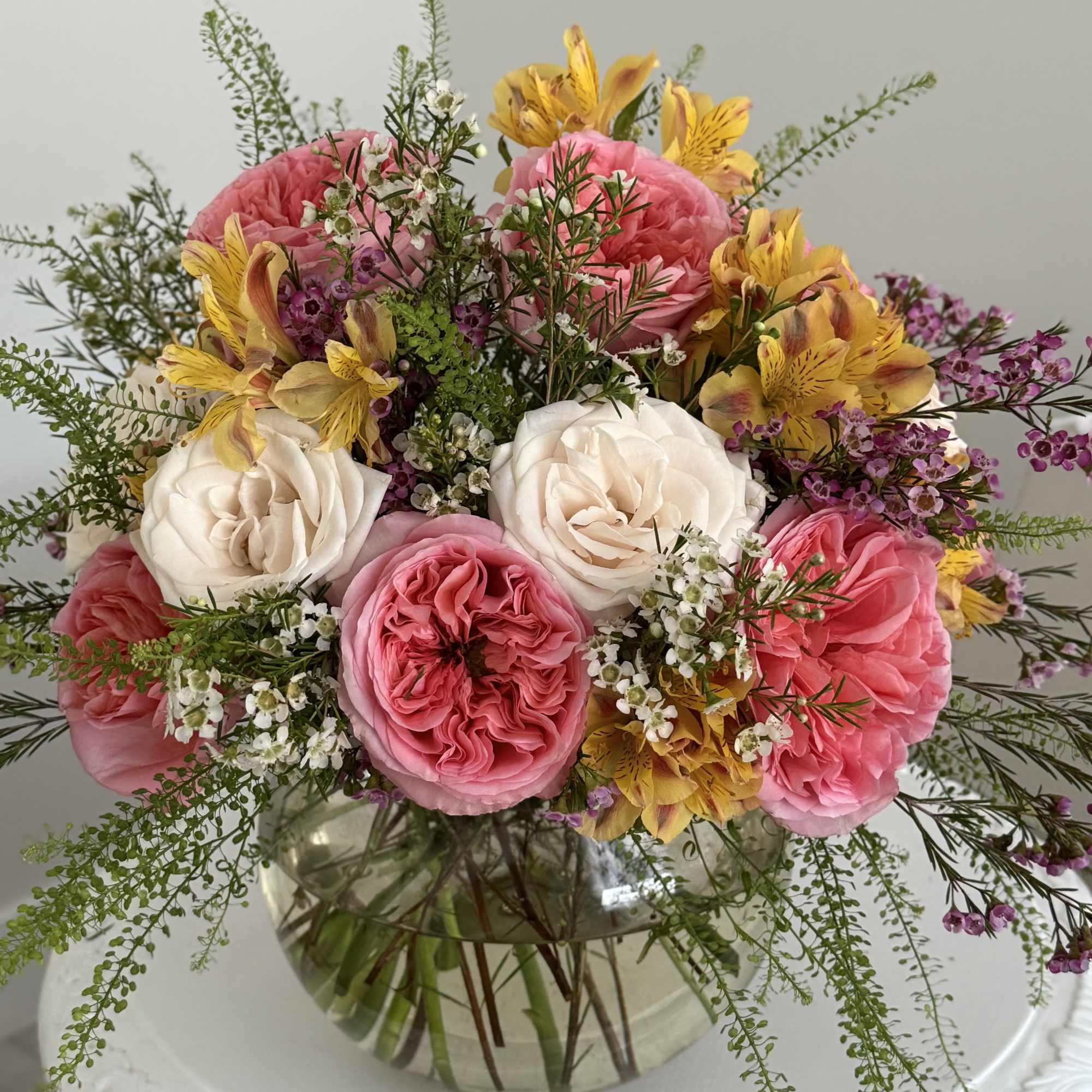 Pink and white roses with yellow flowers in a glass vase
