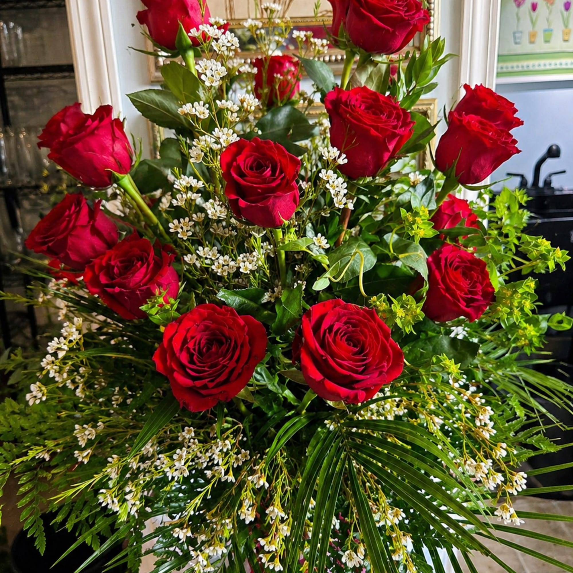 A clustered tower of deep red roses rises above a cloud of