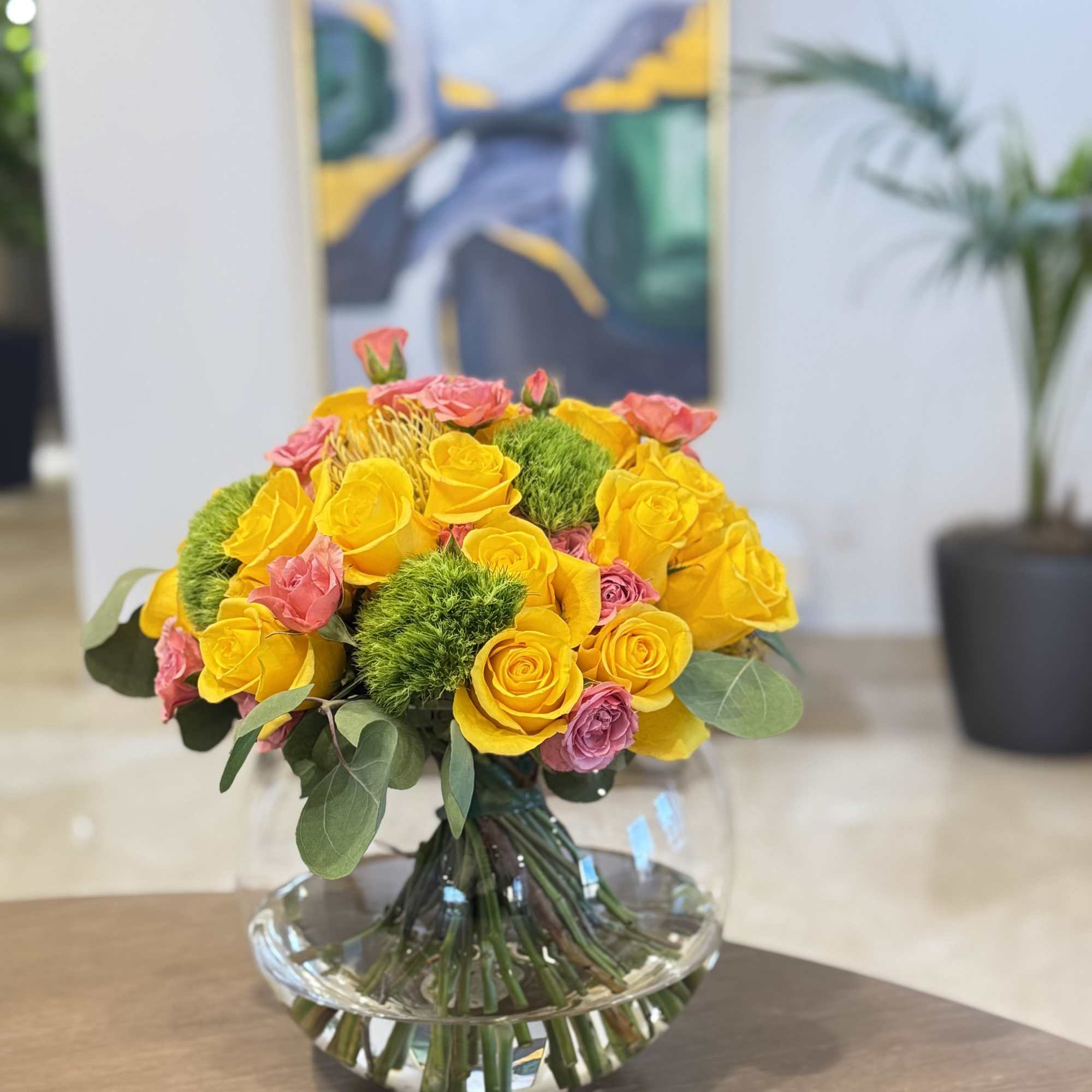 Yellow and pink roses arranged in a clear glass vase
