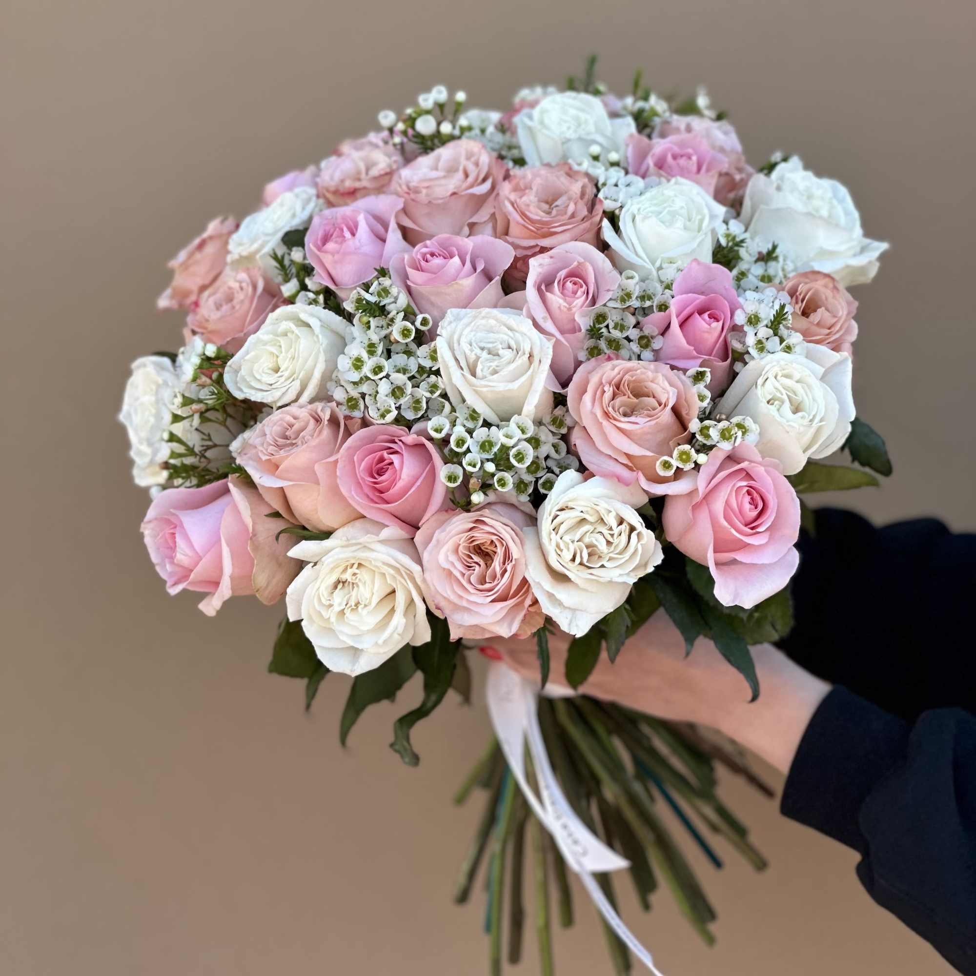 Hand-tied bouquet of pink and white roses with small white filler flowers