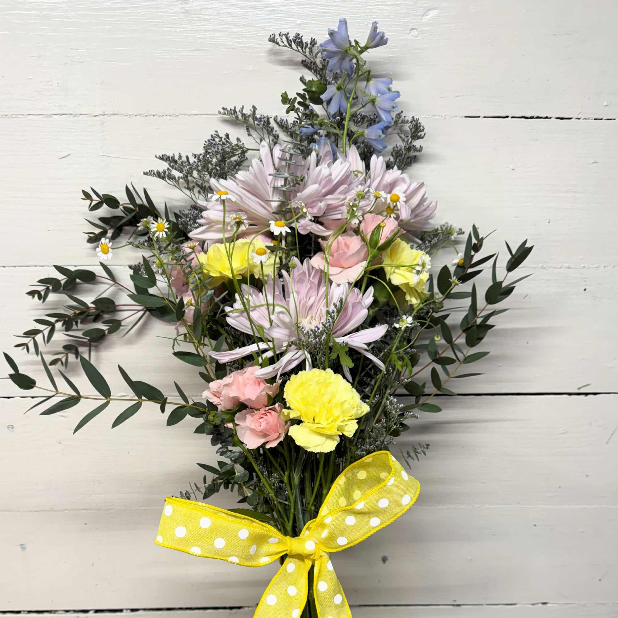 Mixed pastel bouquet with daisies, carnations, and a yellow ribbon