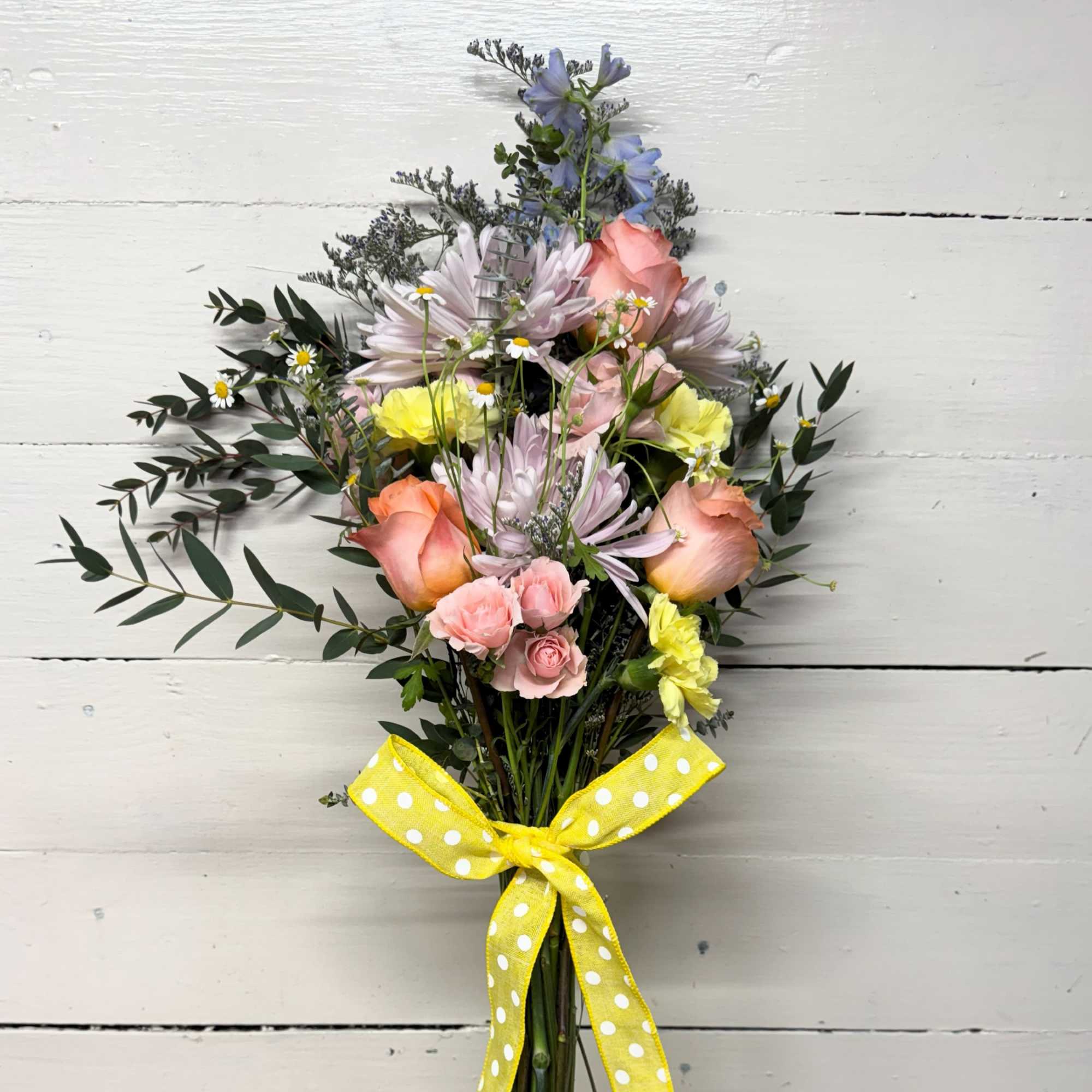 Mixed bouquet of pastel flowers tied with a yellow polka-dot ribbon