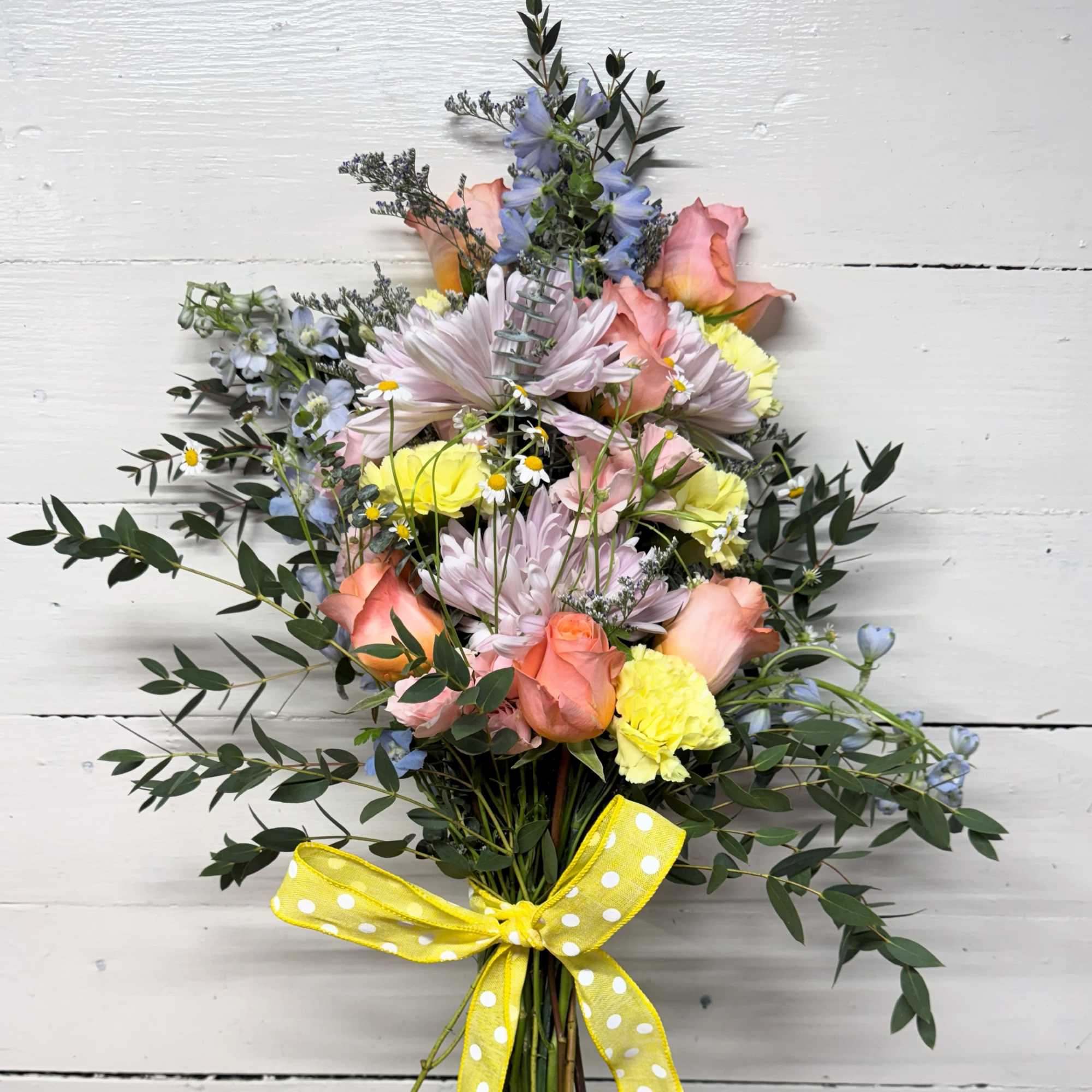Mixed bouquet of pastel flowers tied with a yellow polka-dot ribbon