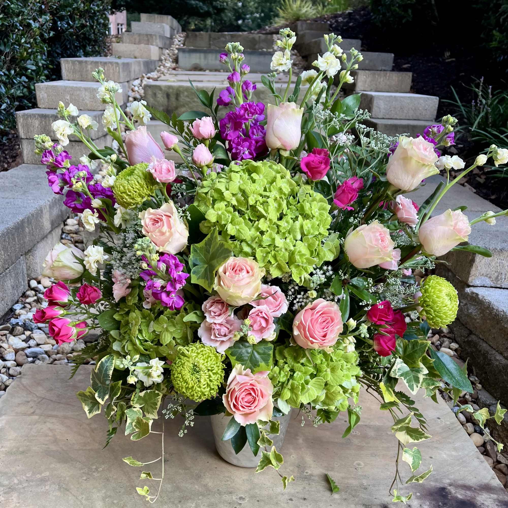 Large bouquet of pink roses, green hydrangeas, and purple flowers in a vase
