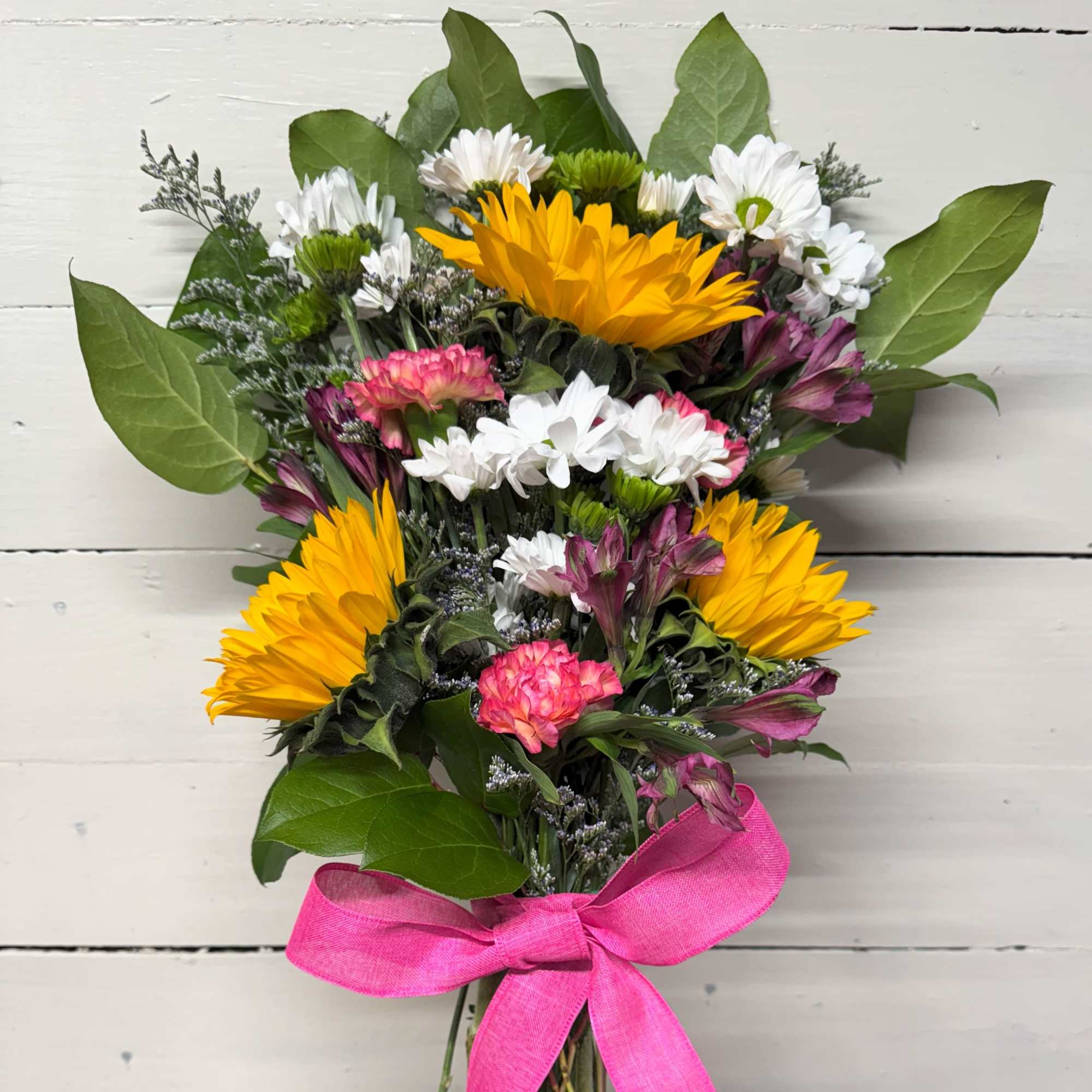 Bouquet of yellow, white, pink, and purple flowers tied with a pink ribbon