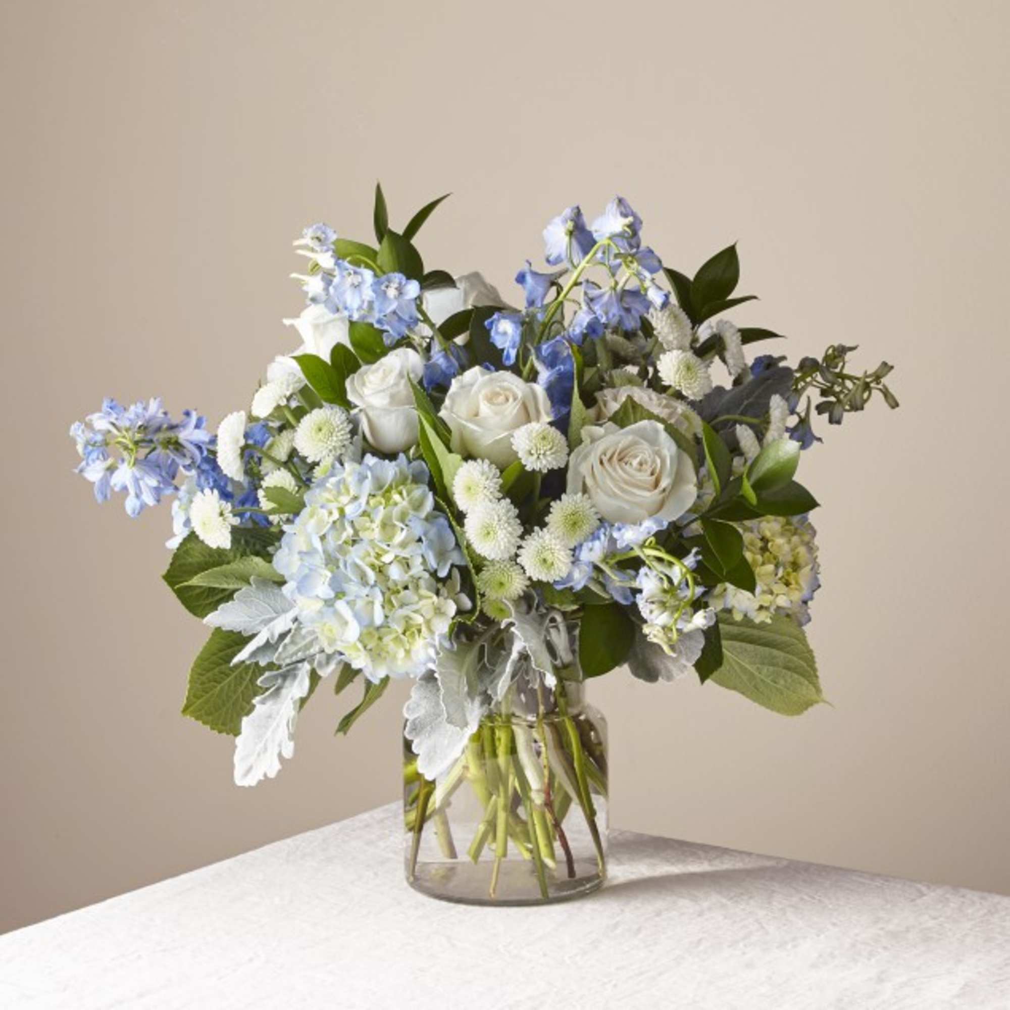 Bouquet of white roses and blue hydrangeas in a clear glass vase