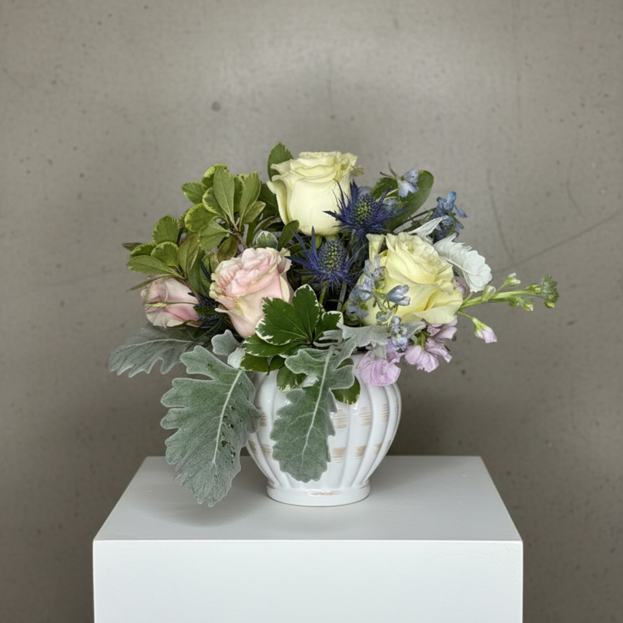 Mixed bouquet in a white vase with pale roses and blue thistle