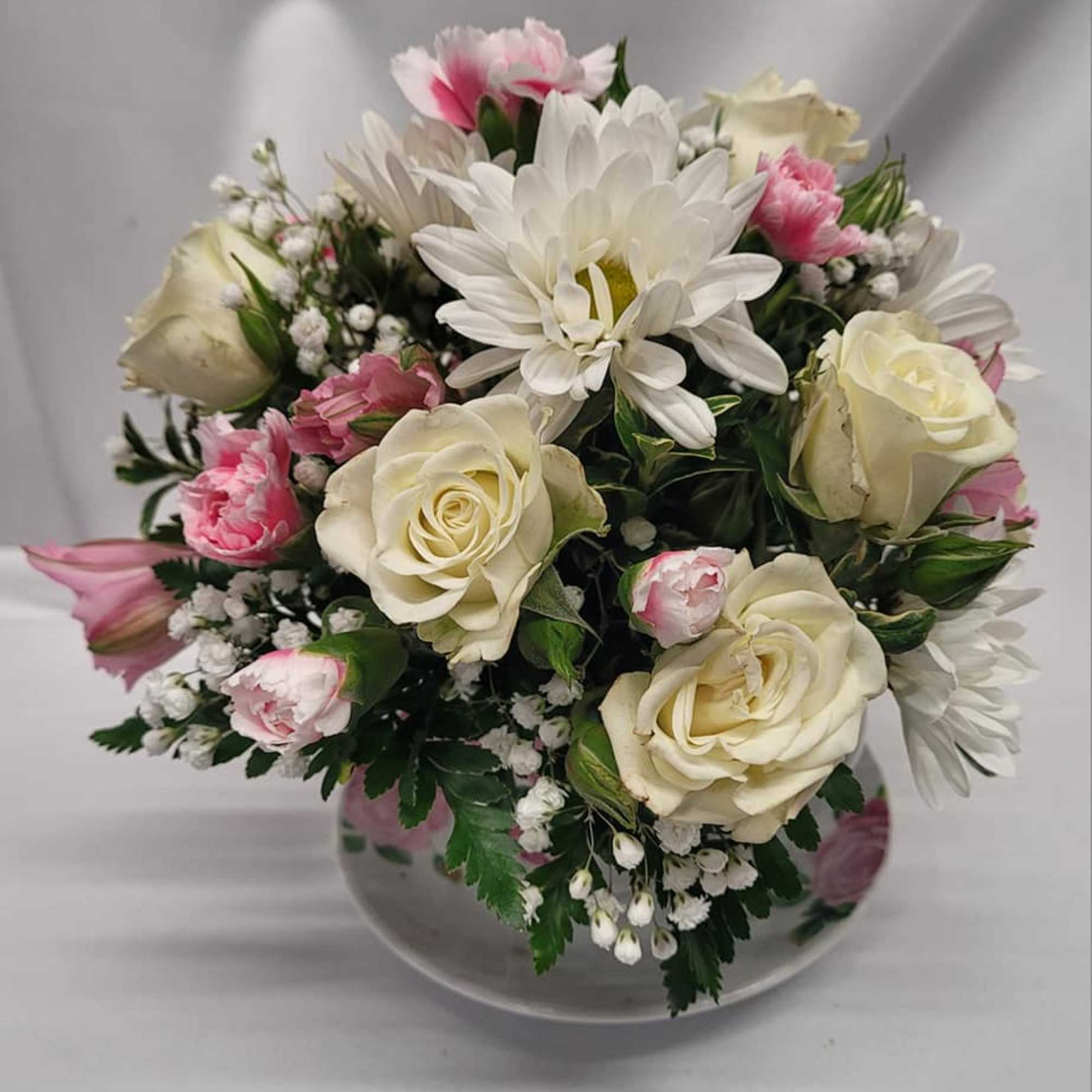 A cozy cluster of mixed roses, daisies, alstroemeria and chrysanthemums arranged in