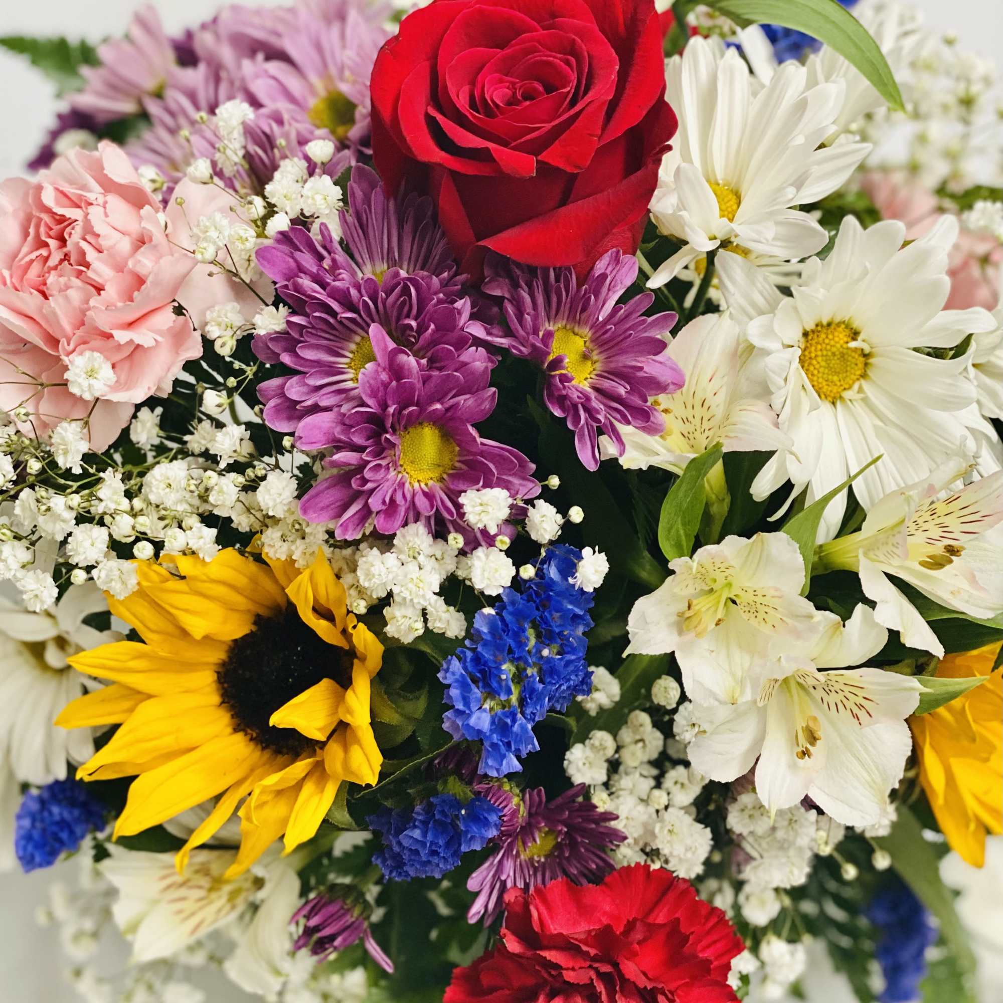 Mixed bouquet with a red rose, sunflowers, daisies, and carnations