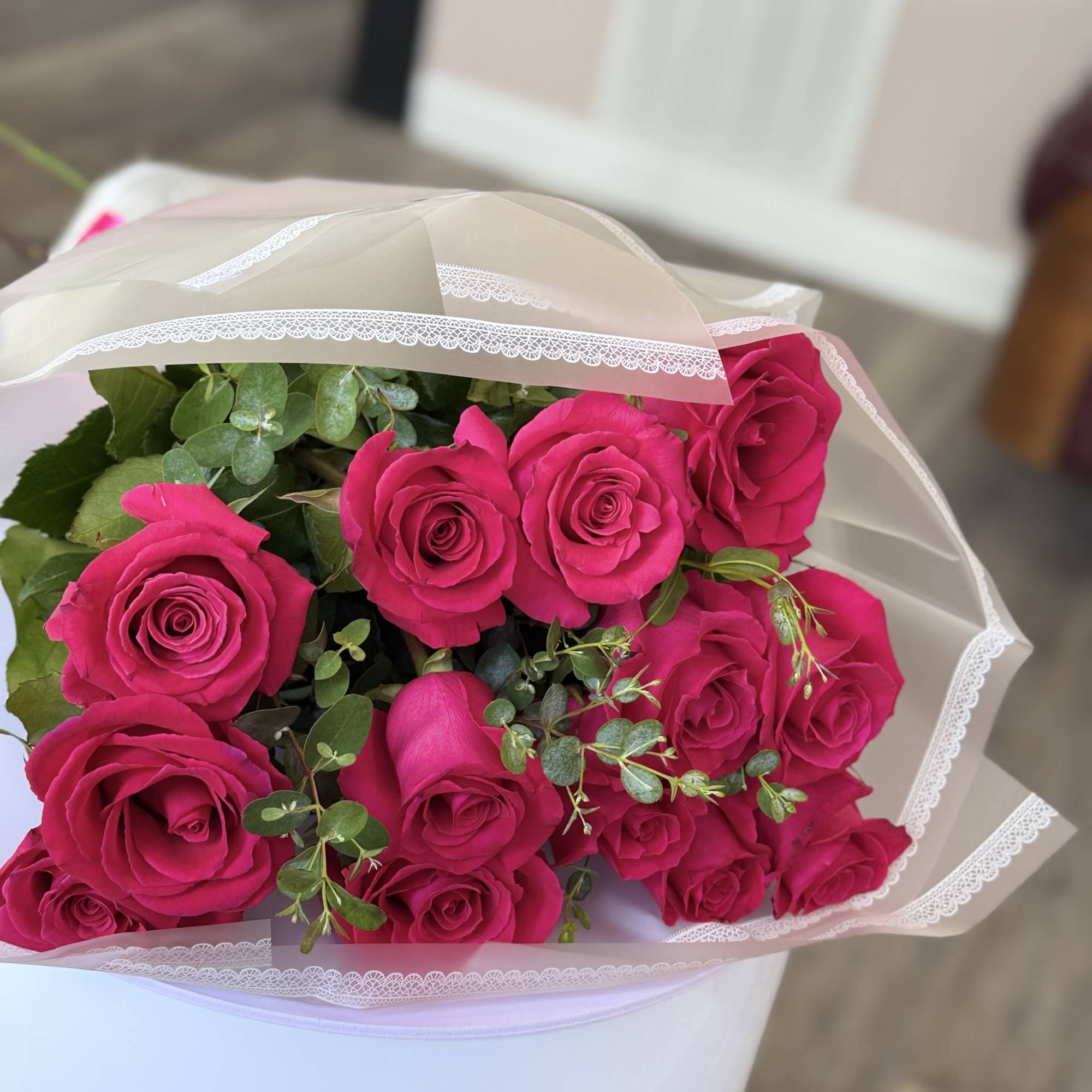 A dense cluster of vivid hot pink roses takes center stage in