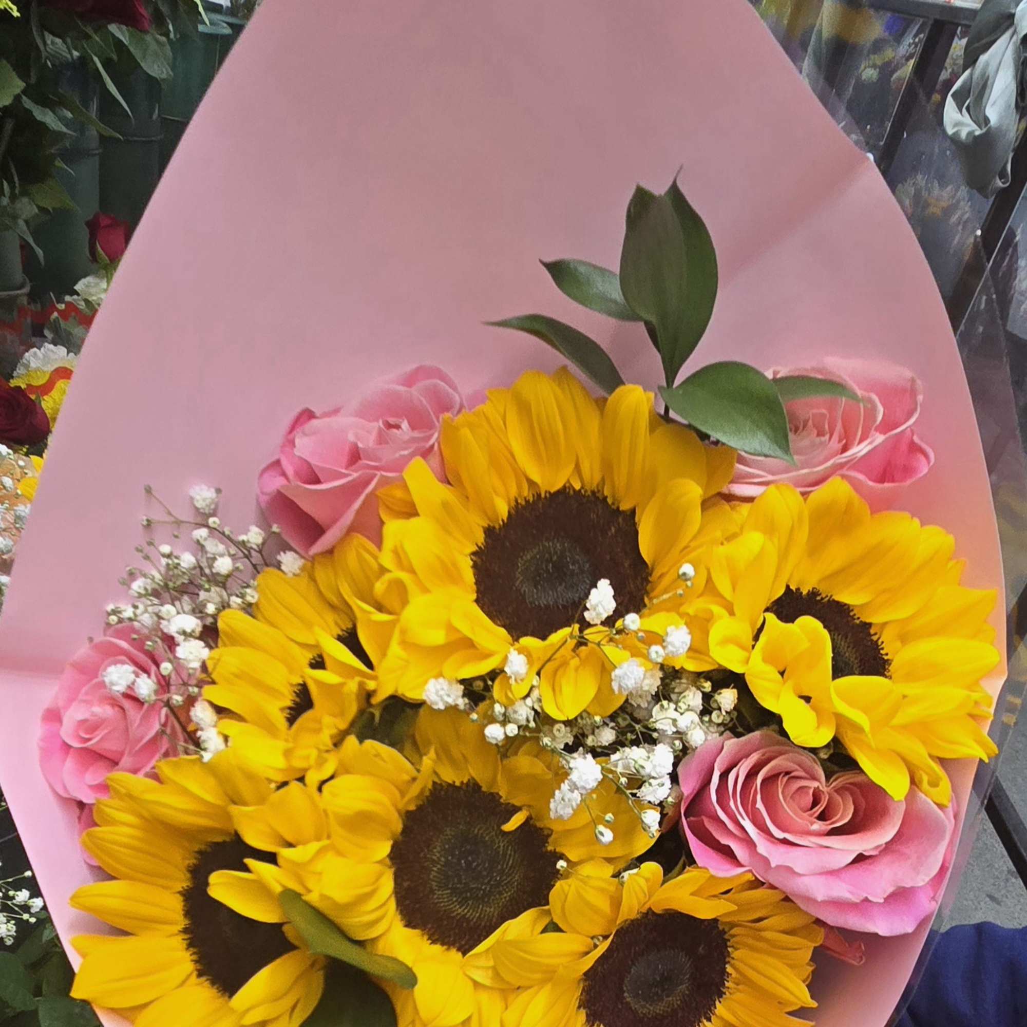 Bouquet of yellow sunflowers and pink roses wrapped in pink paper