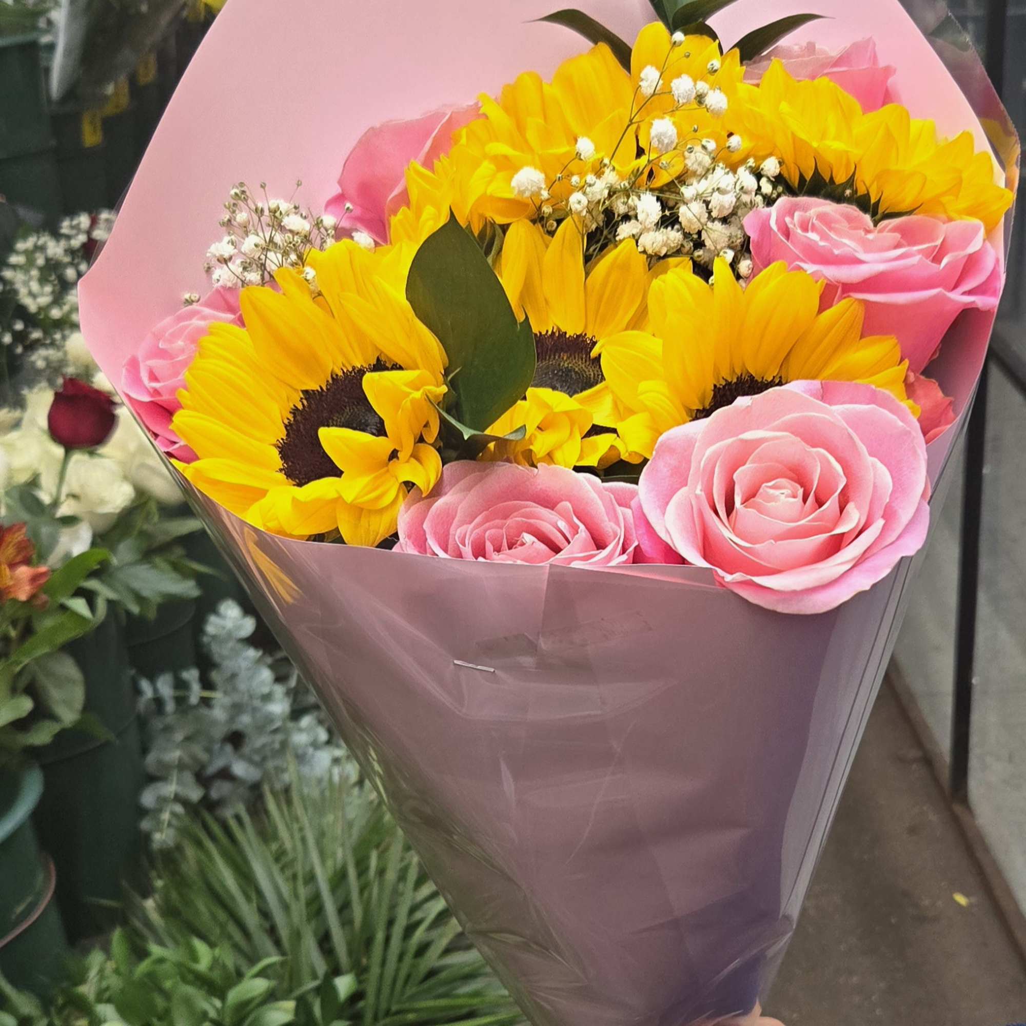 Bouquet of yellow sunflowers and pink roses wrapped in pink paper