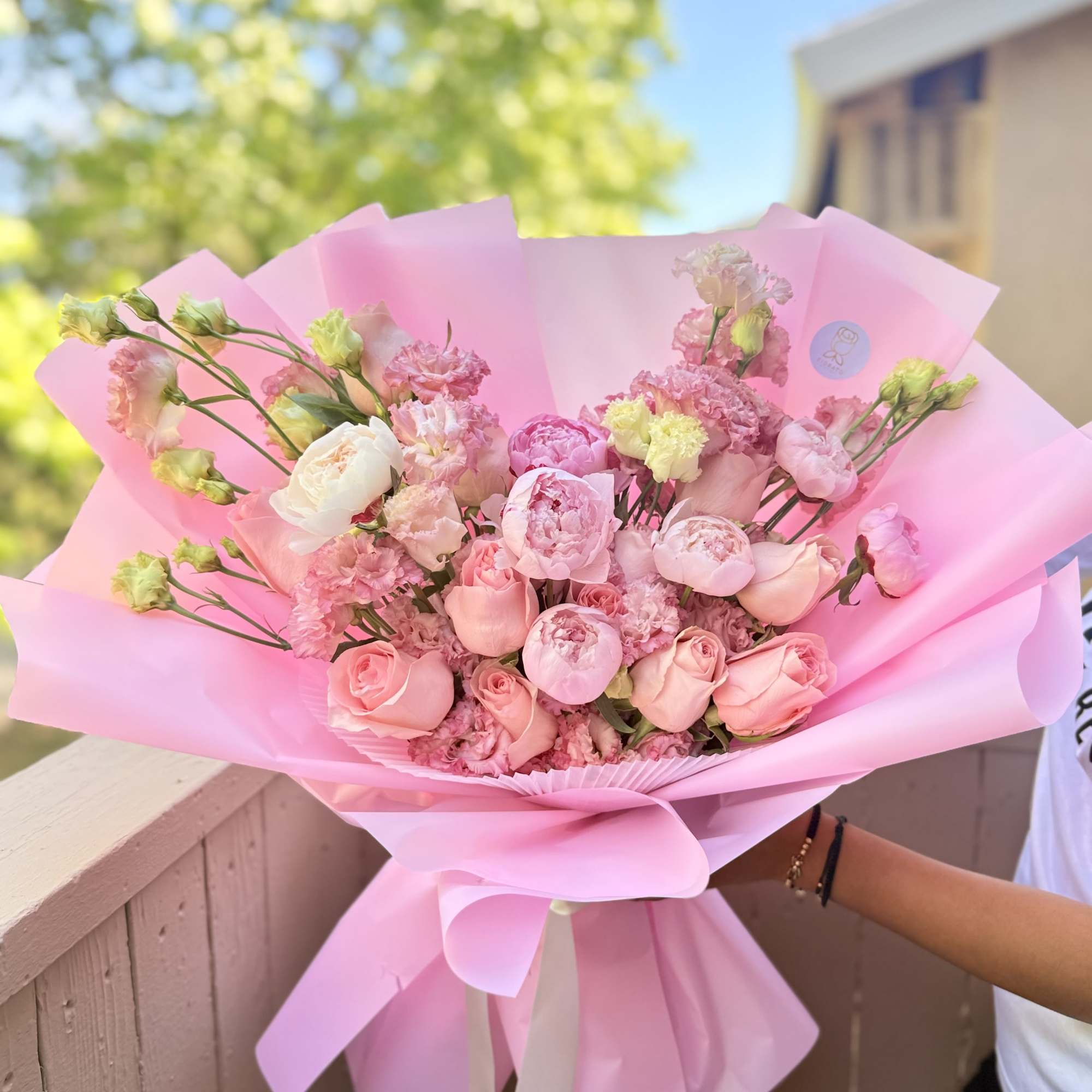 Soft blush peonies and rounded pink roses take center stage in this