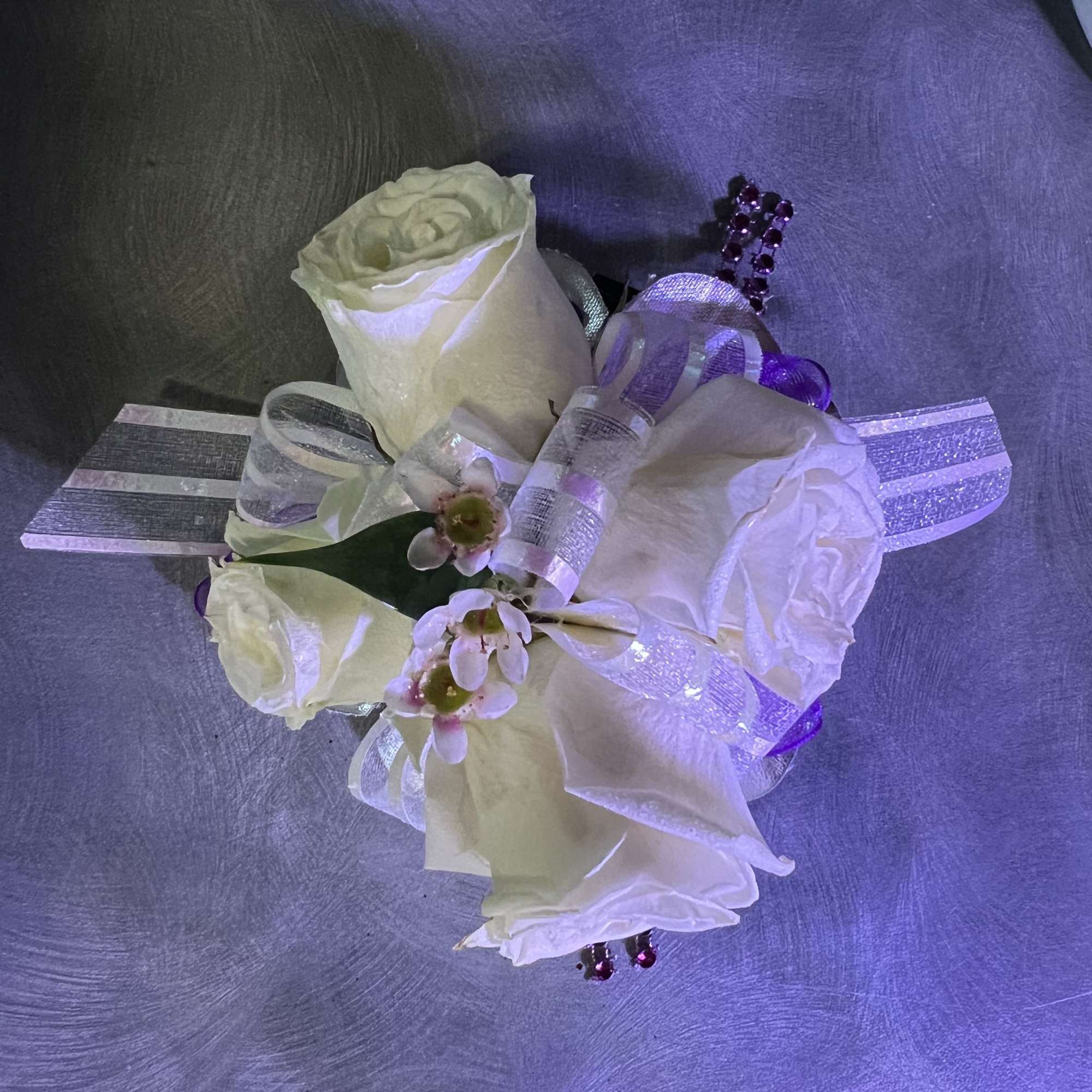 White rose corsage with purple ribbon and bead accents
