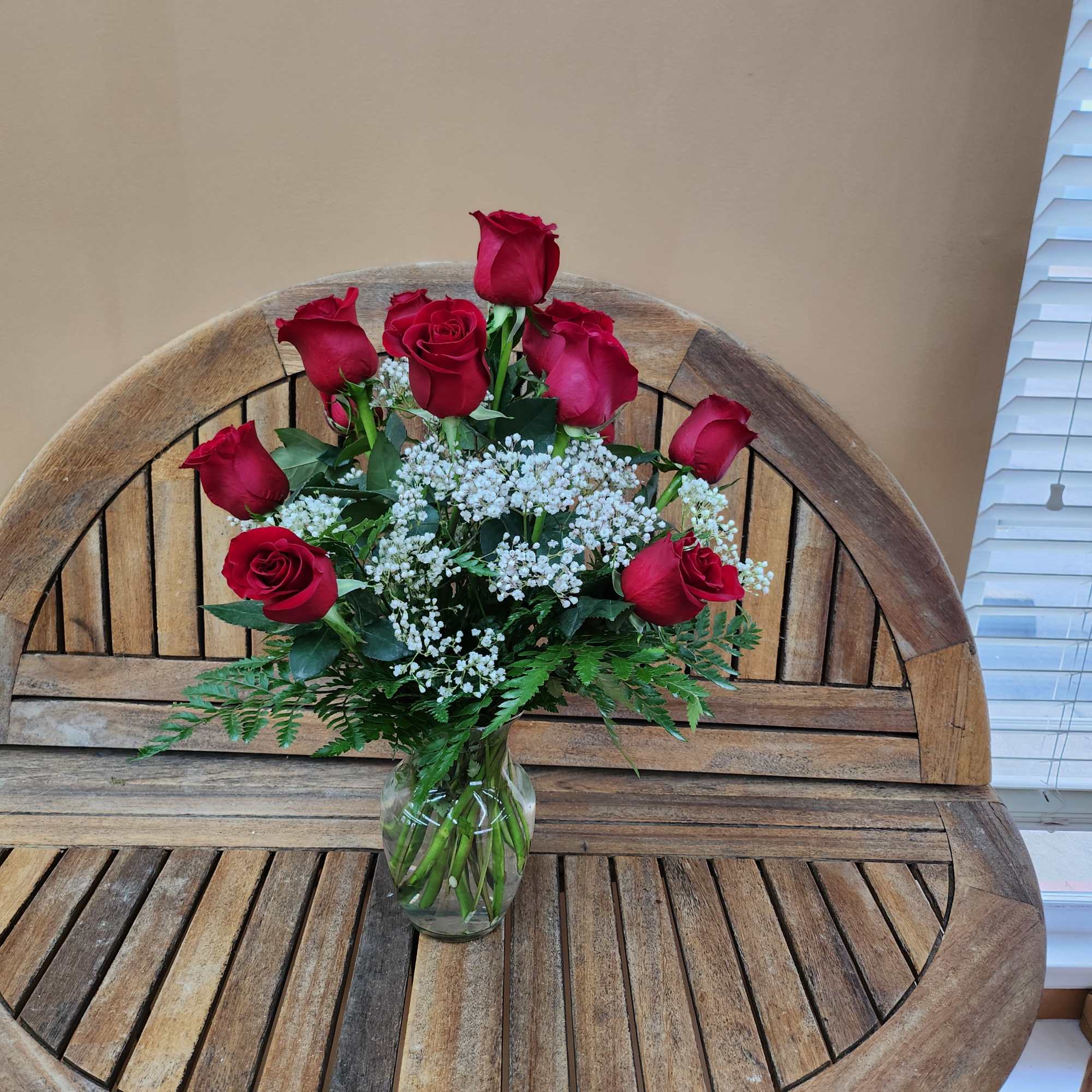 Red roses arranged in a clear glass vase with white filler flowers