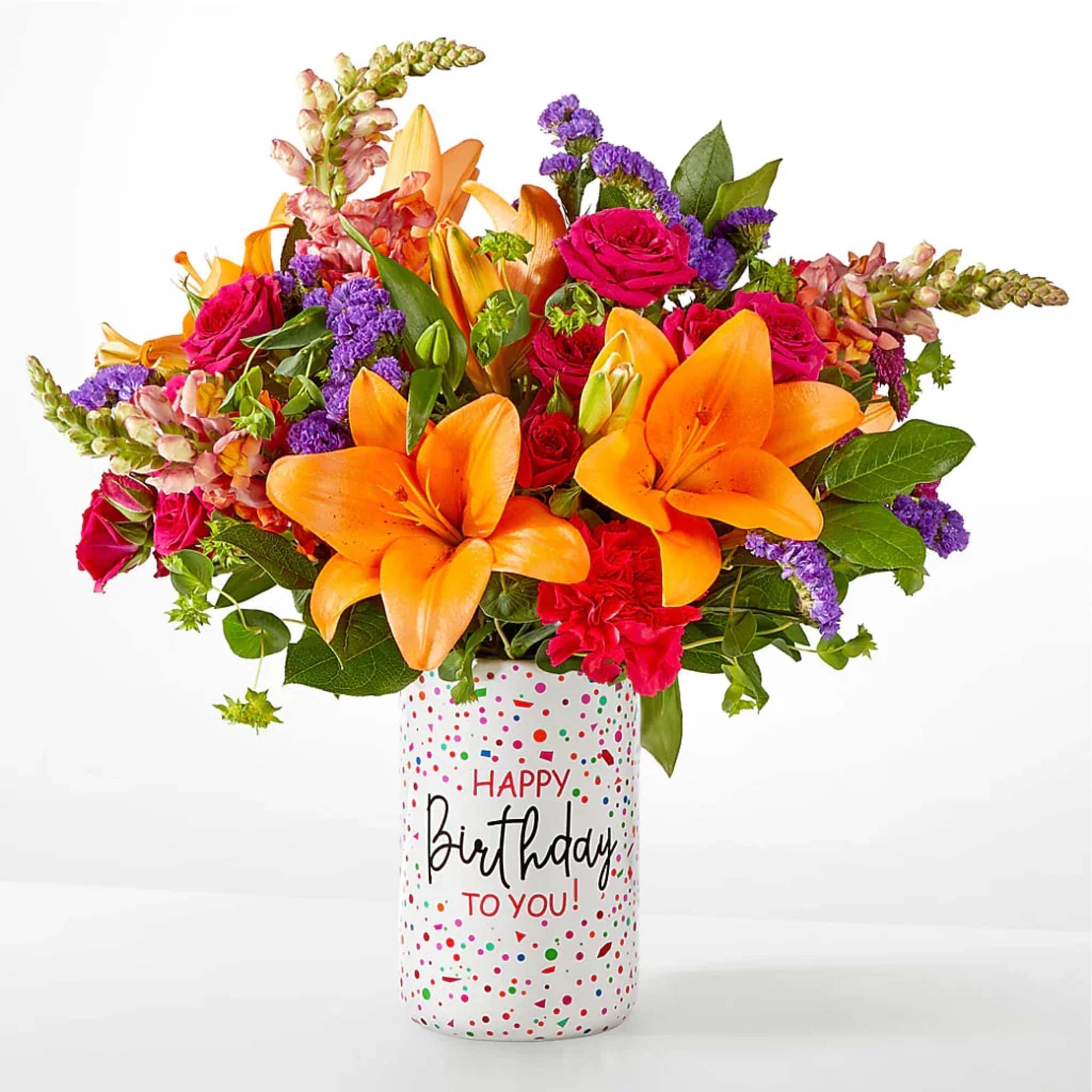 Bouquet of orange lilies, pink roses, and purple flowers in a birthday vase