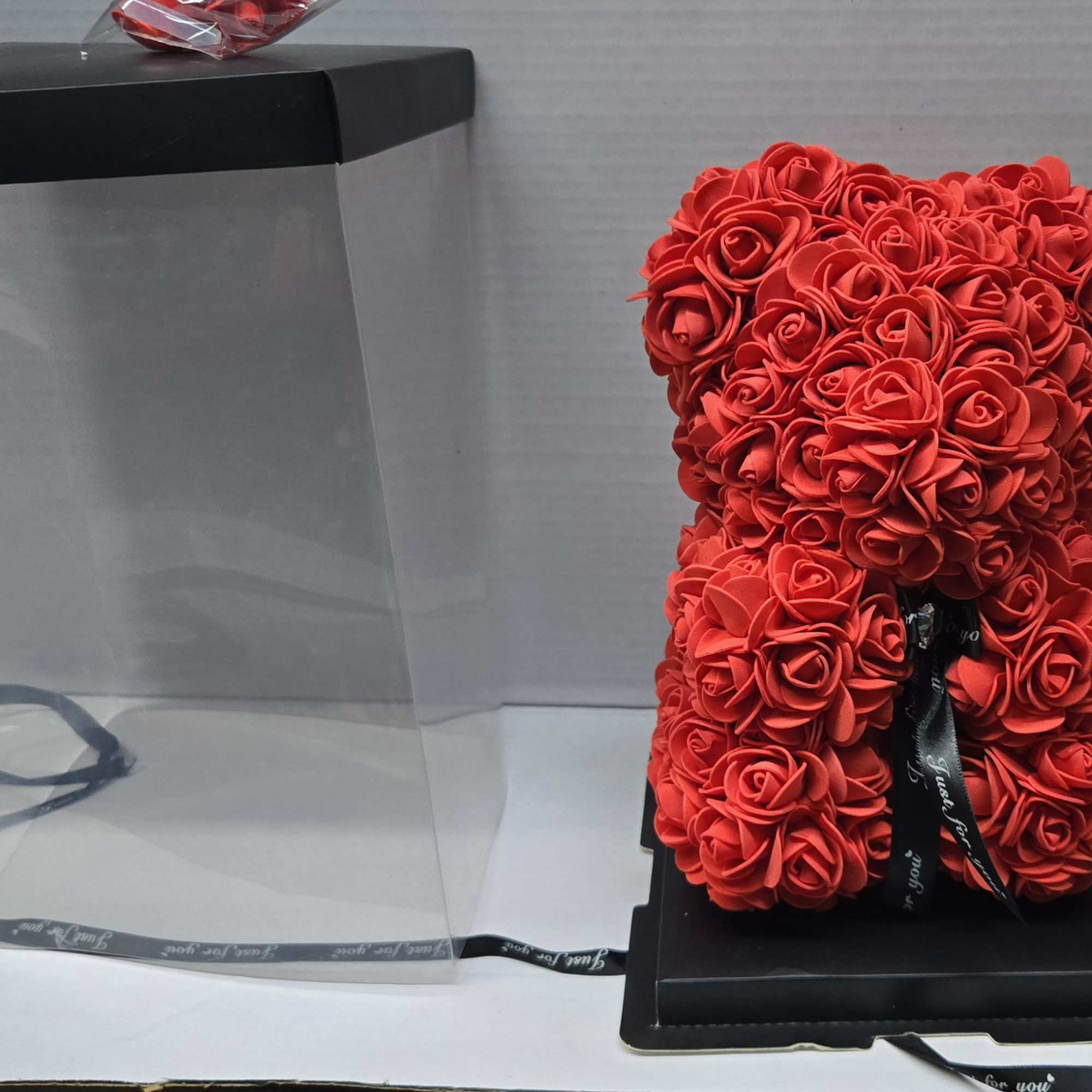 Red rose teddy bear in a clear gift box with a black lid