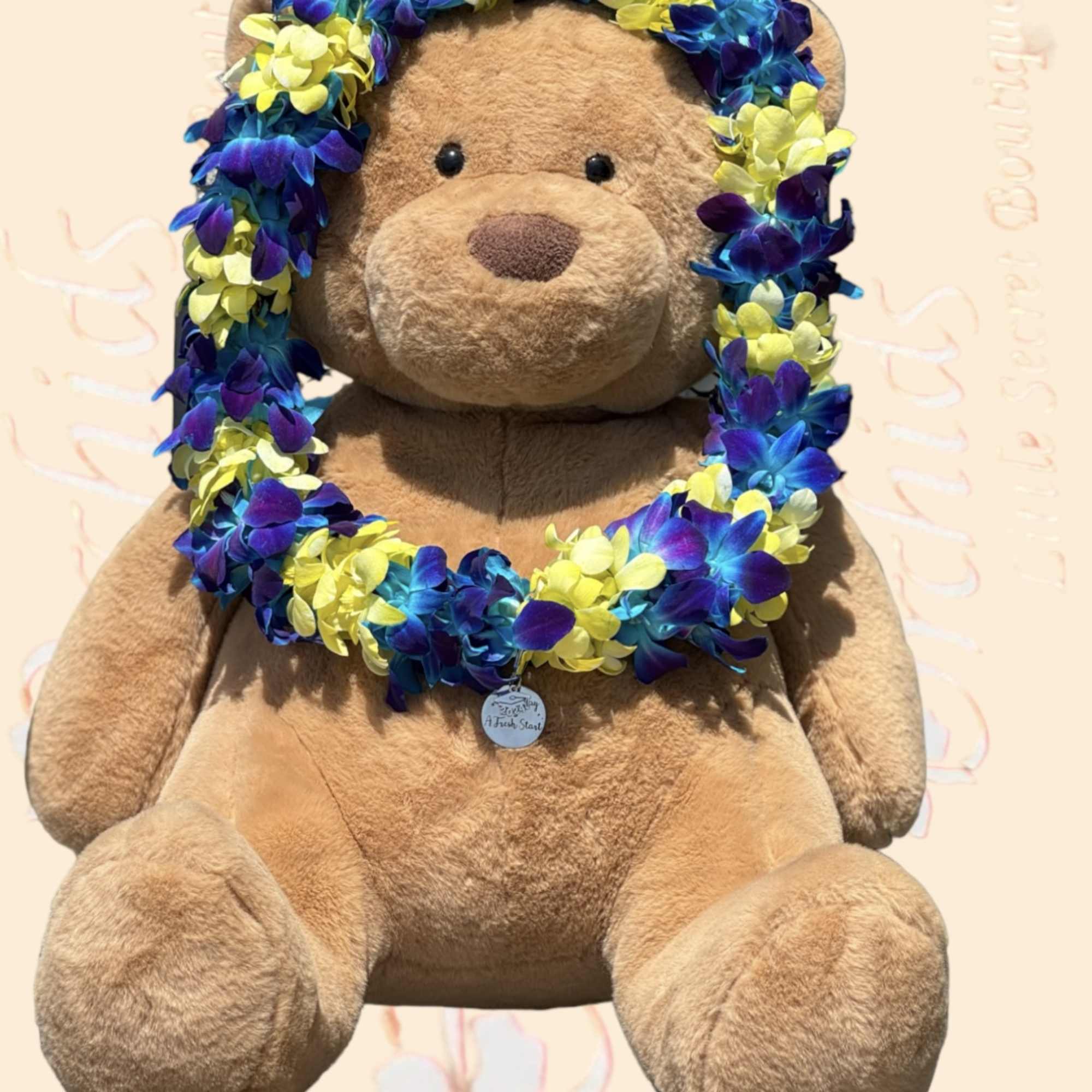 Teddy bear wearing a blue, purple, and yellow flower lei