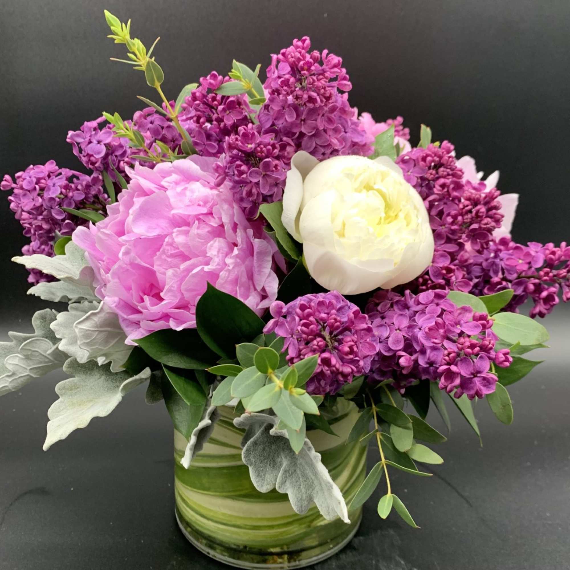 Pink and white flowers arranged in a glass vase with purple blooms