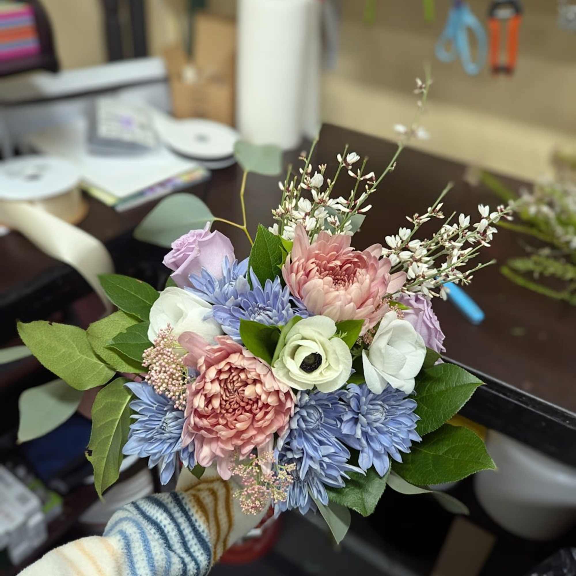 Handheld bouquet of pastel flowers in pink, blue, white, and lavender