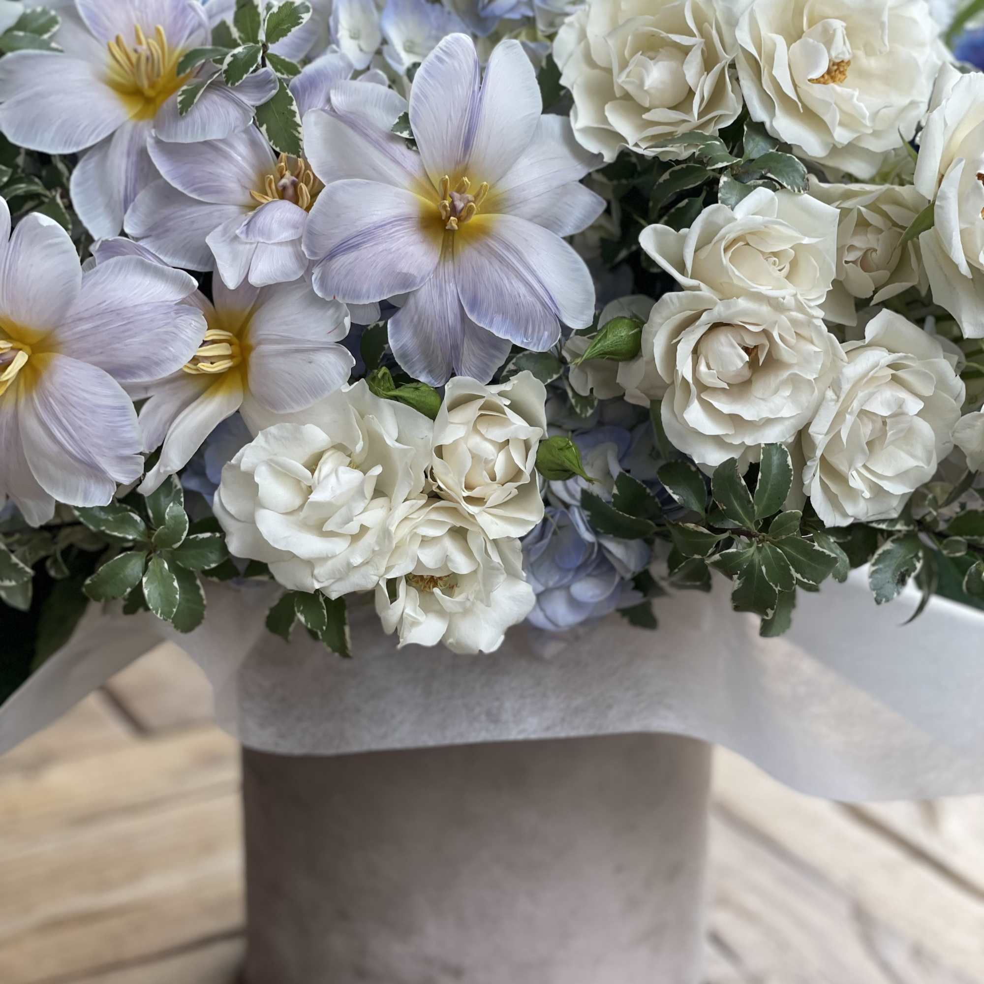 Bouquet of pale lavender and white flowers in a gray hatbox