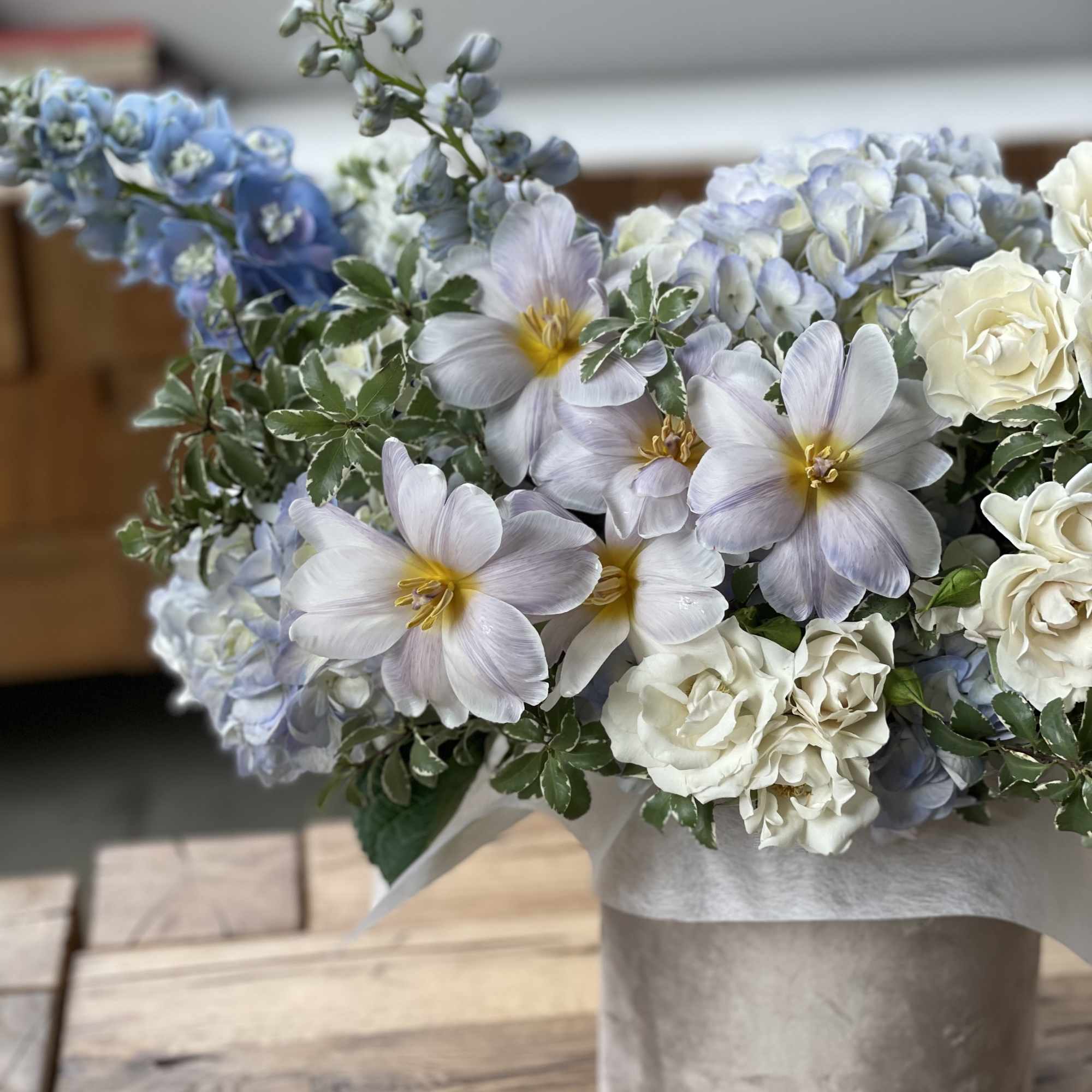 Bouquet of pale blue and white flowers in a beige hatbox