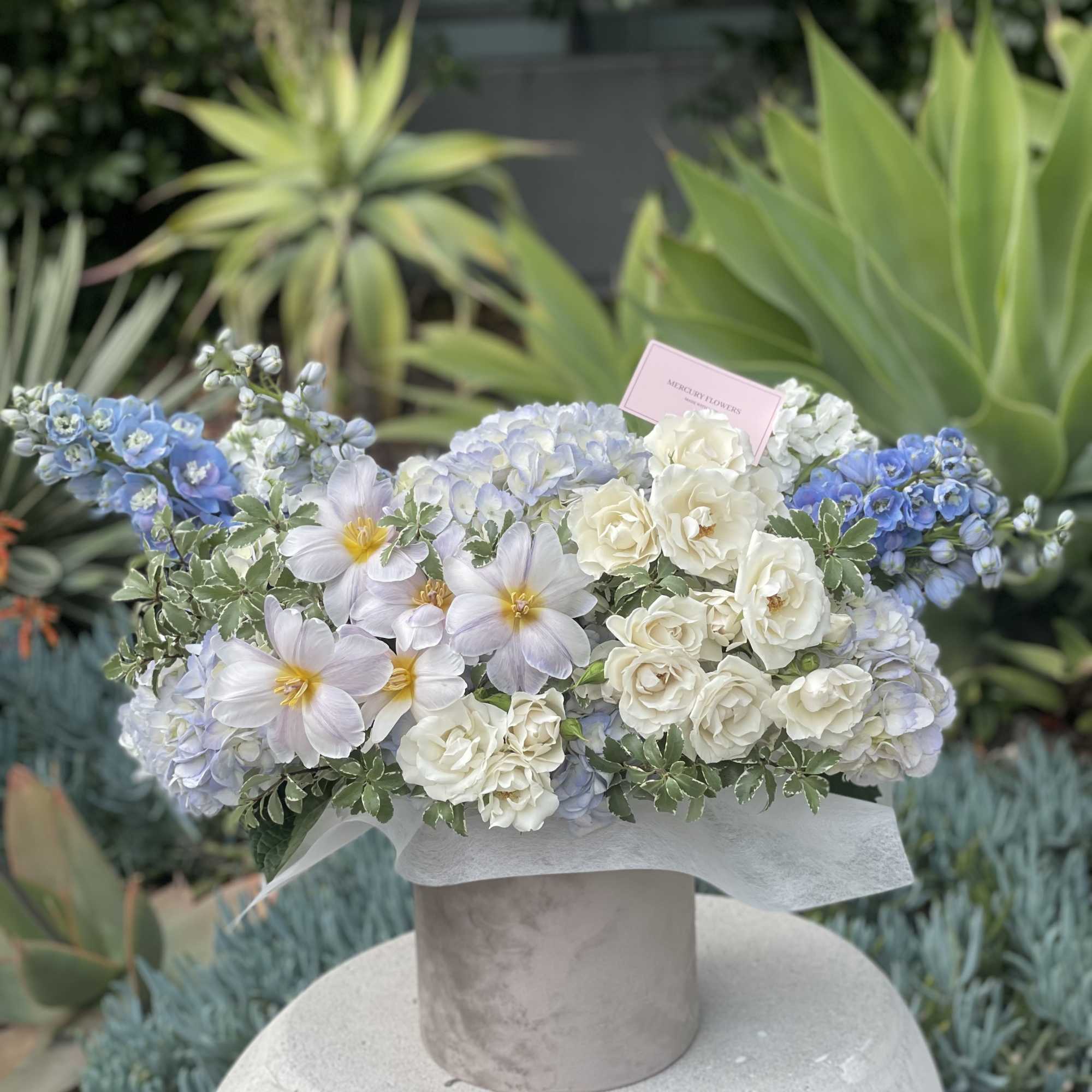 Blue and white floral arrangement in a round box