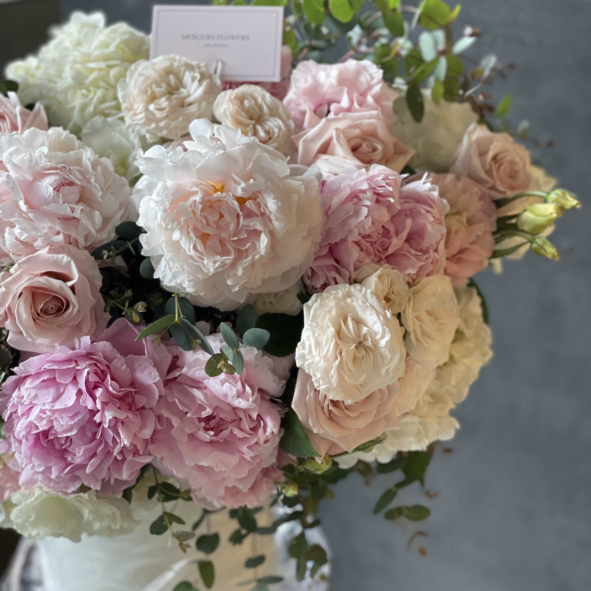 Pink and white roses arranged in a clear vase with greenery