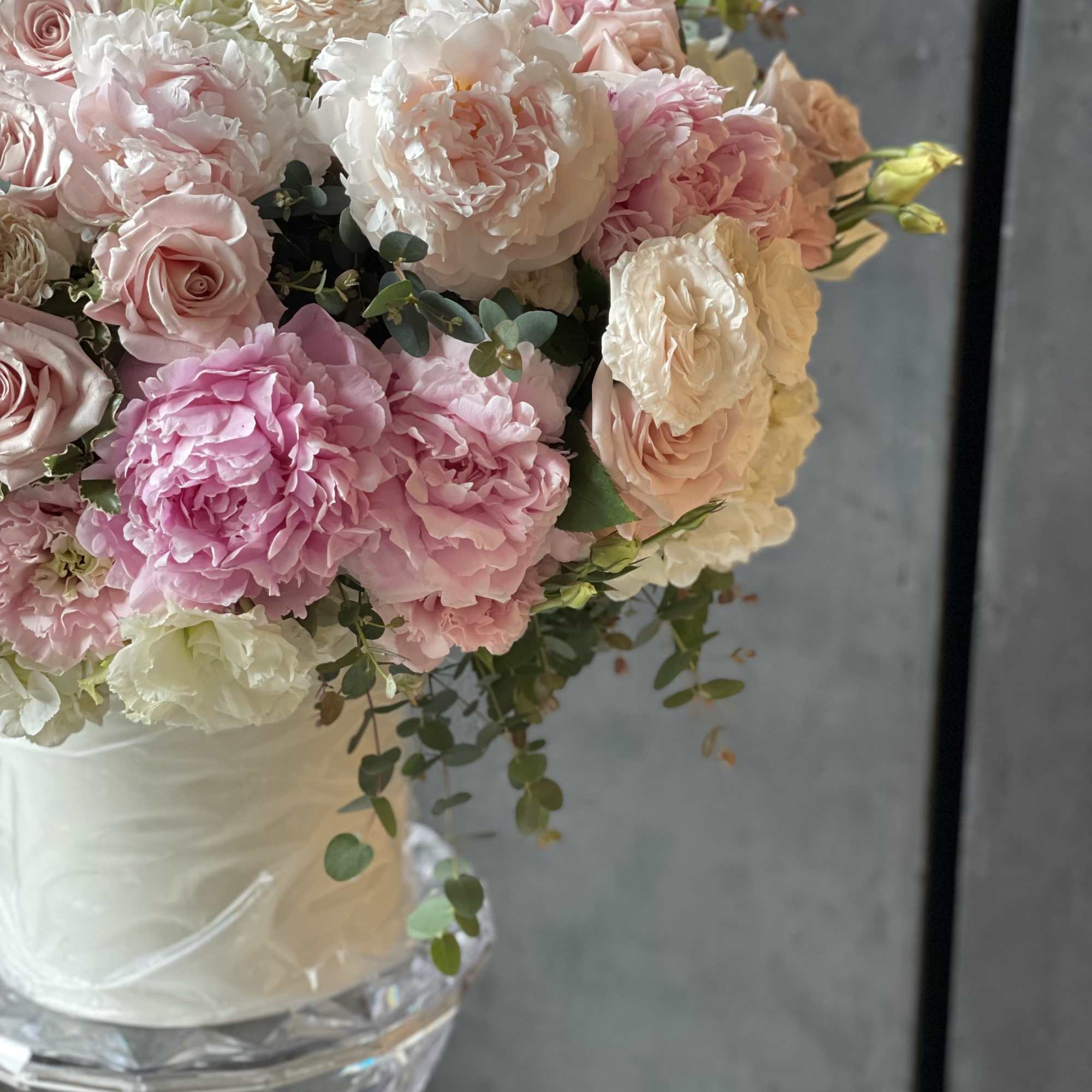 Pastel bouquet of roses and peonies in a white vase