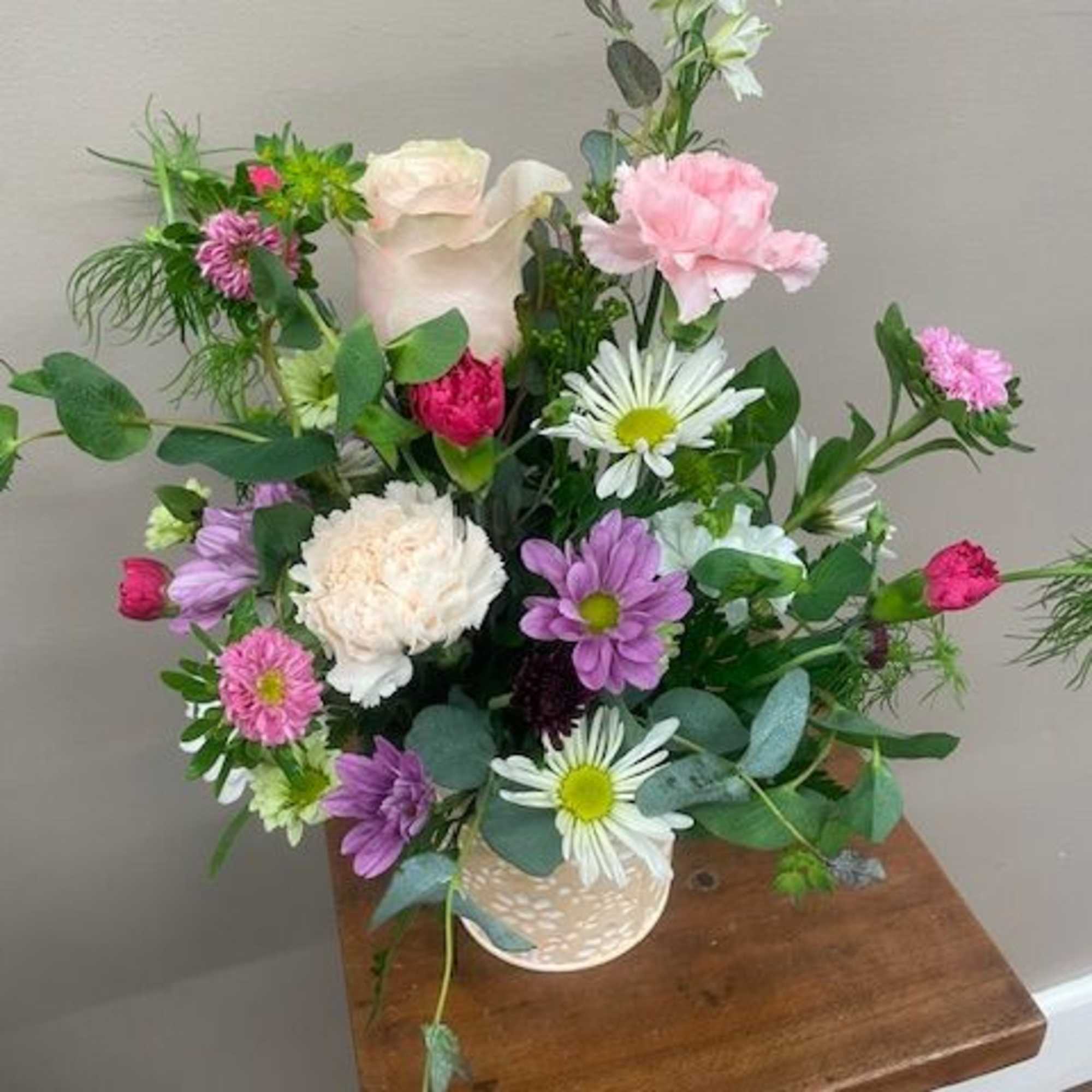 Mixed bouquet in a patterned vase with pink, white, and purple flowers