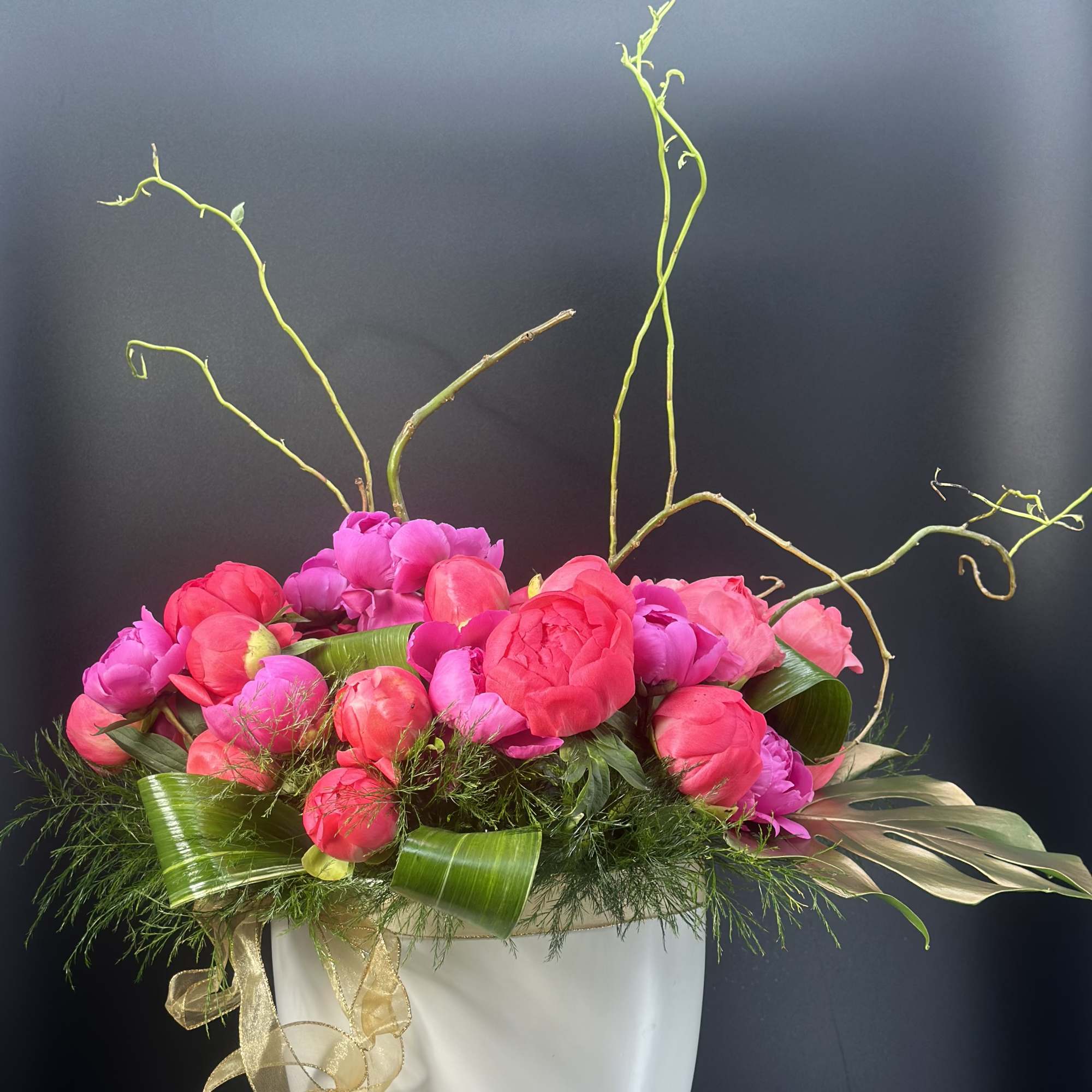 Pink and magenta flowers arranged in a white vase with curly branches
