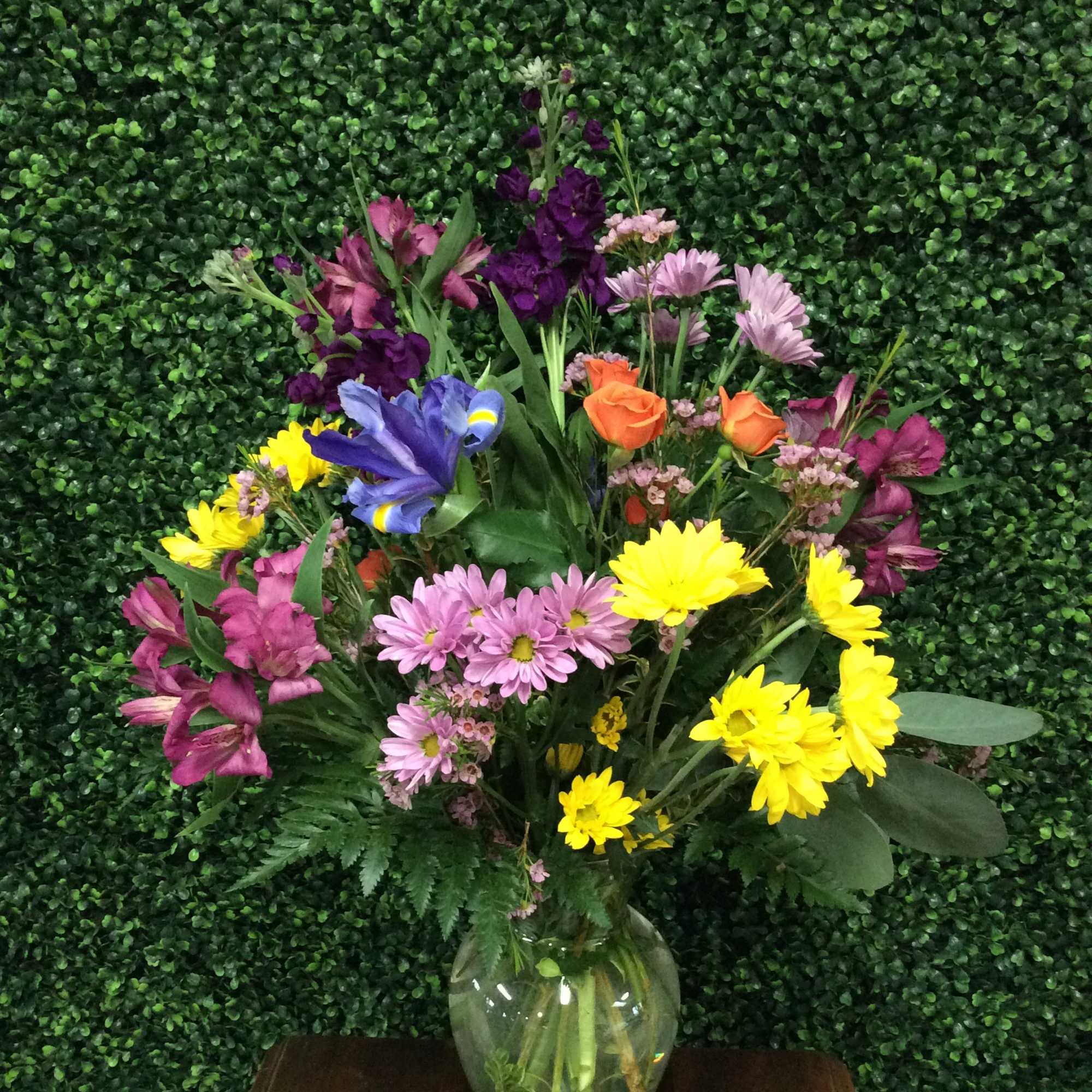 Mixed bouquet in a glass vase with purple, pink, yellow, and orange flowers