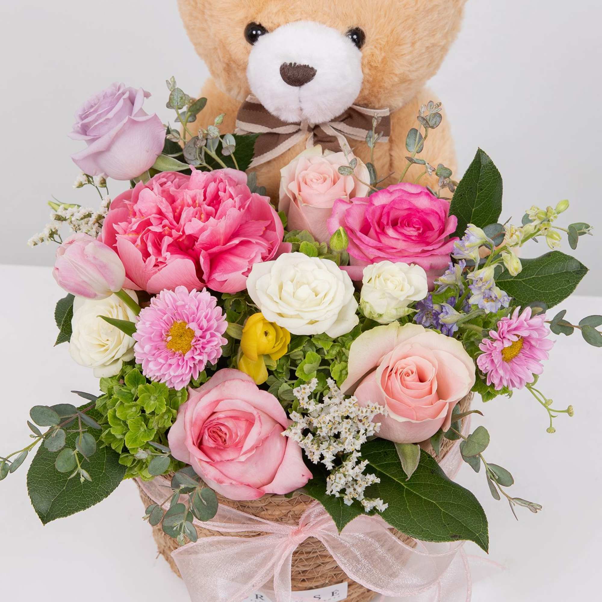A soft mix of pink and white blooms with a cuddly teddy