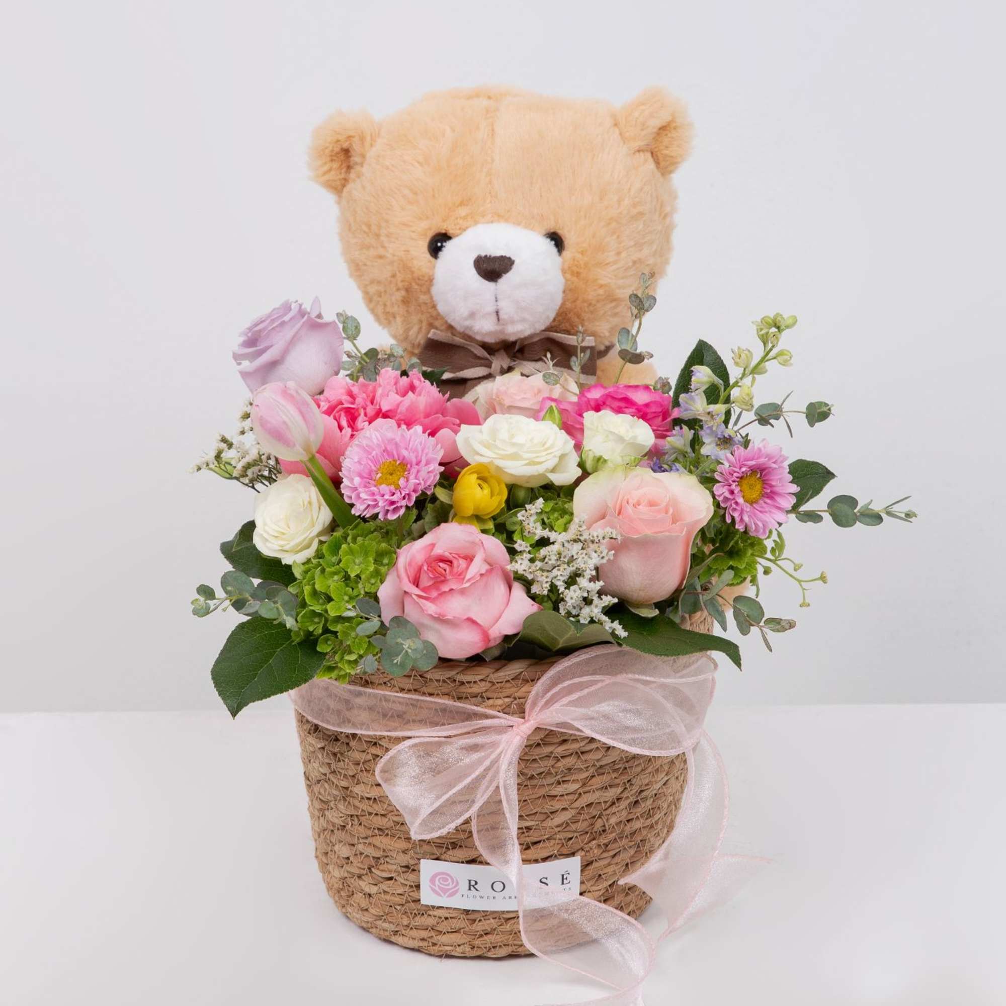 A soft mix of pink and white blooms with a cuddly teddy