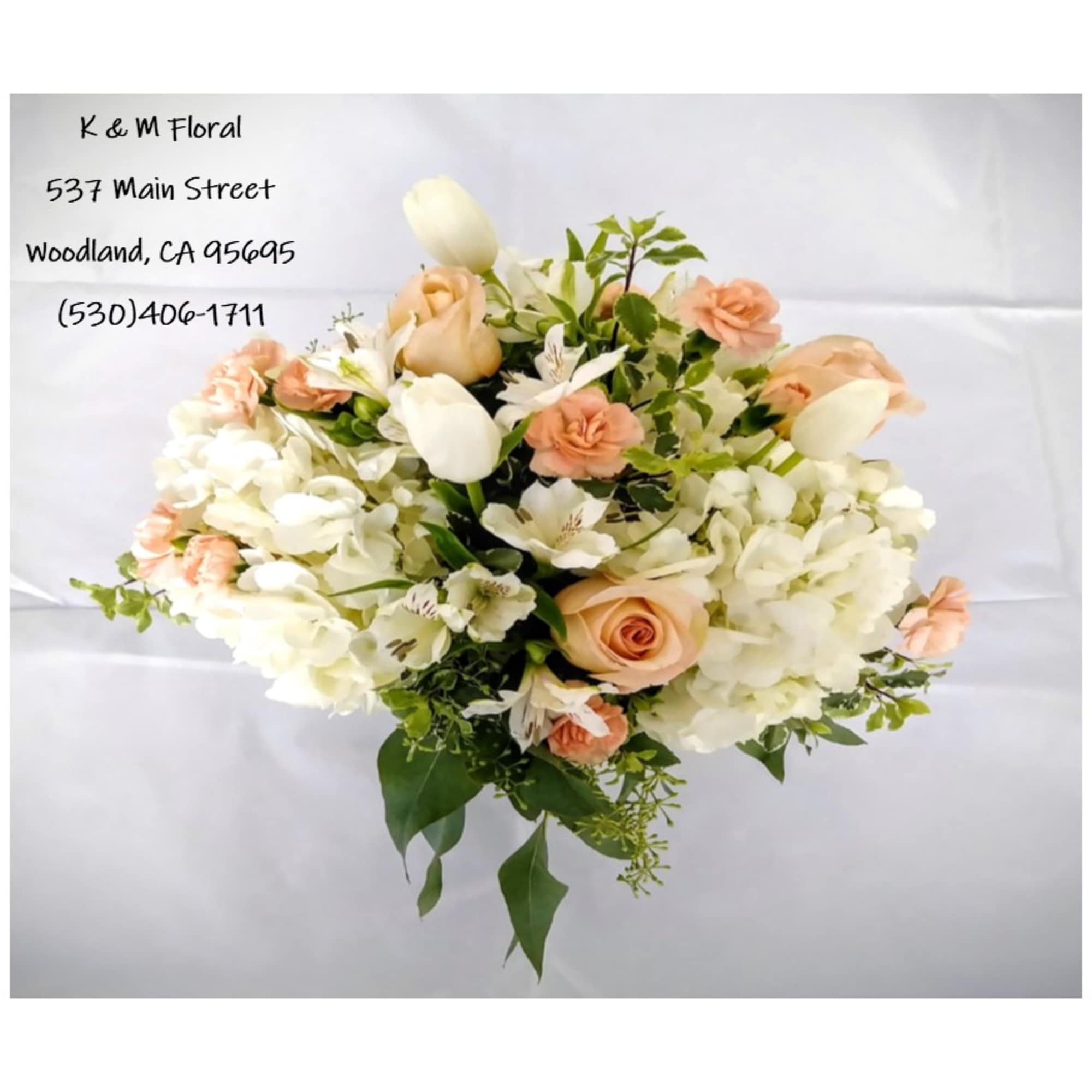 White hydrangea accented with peach roses, white tulips, peach mini carnation and