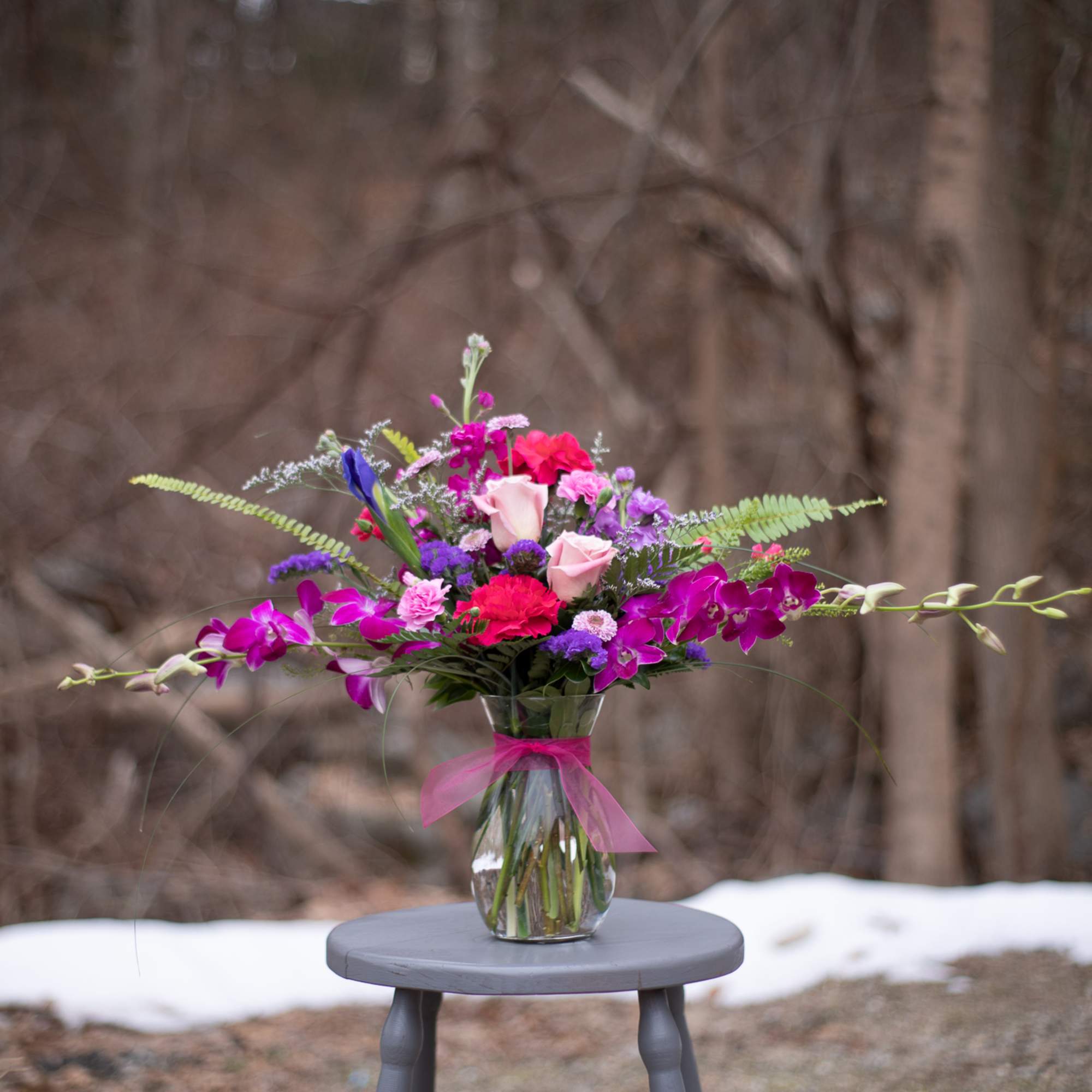 Mixed pink and purple bouquet in a glass vase with a ribbon