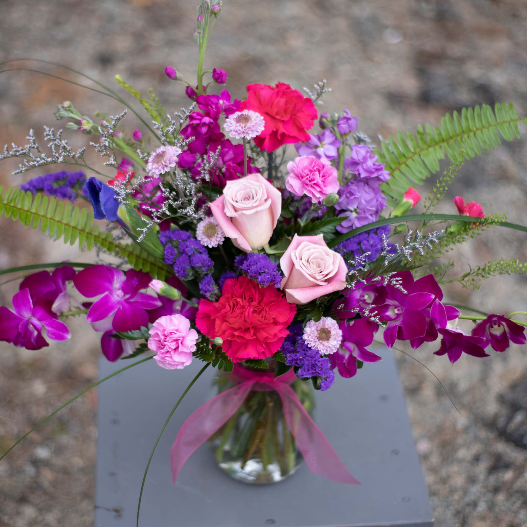 Mixed bouquet of pink, purple, and red flowers in a glass vase