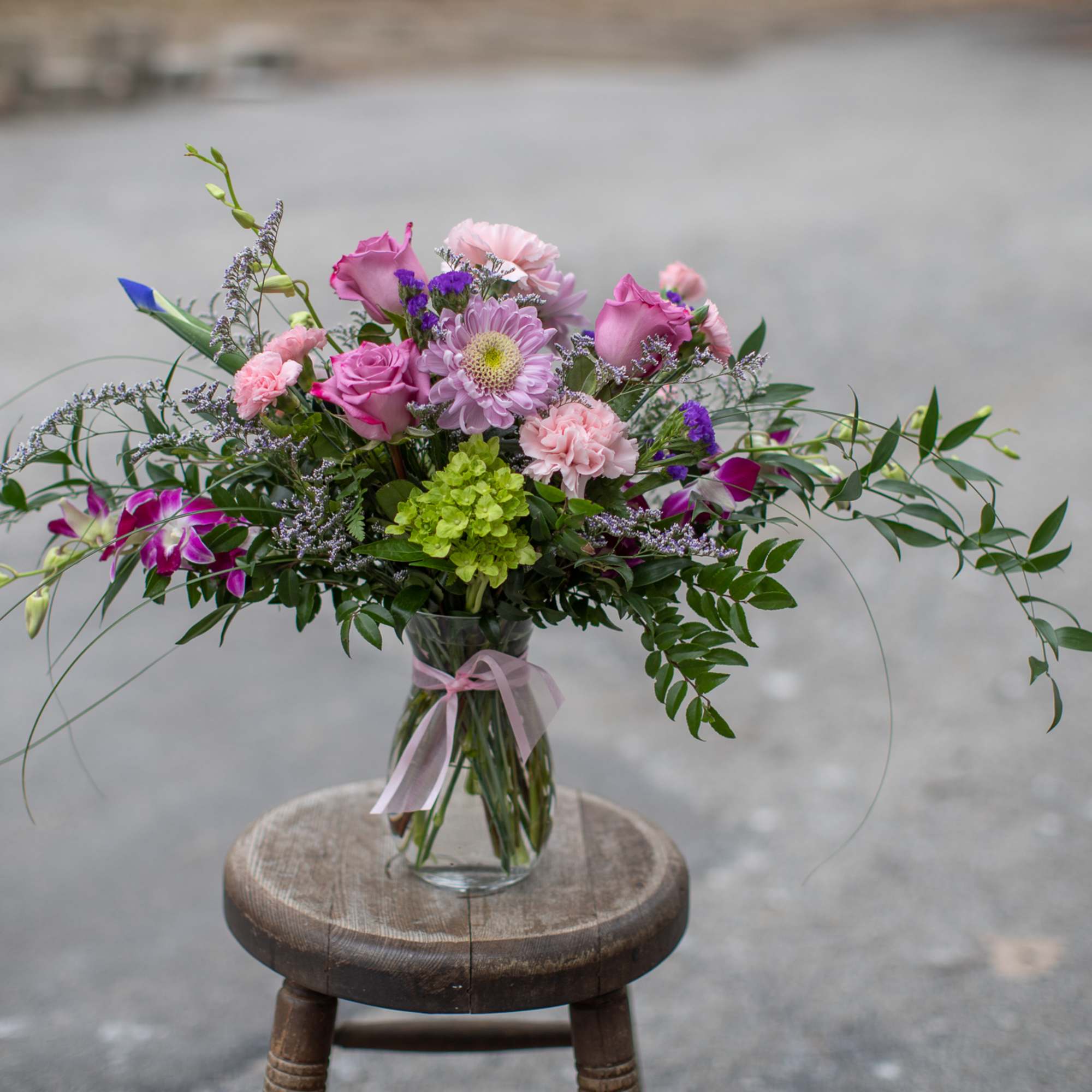 Pink and purple mixed bouquet in a clear glass vase with ribbon