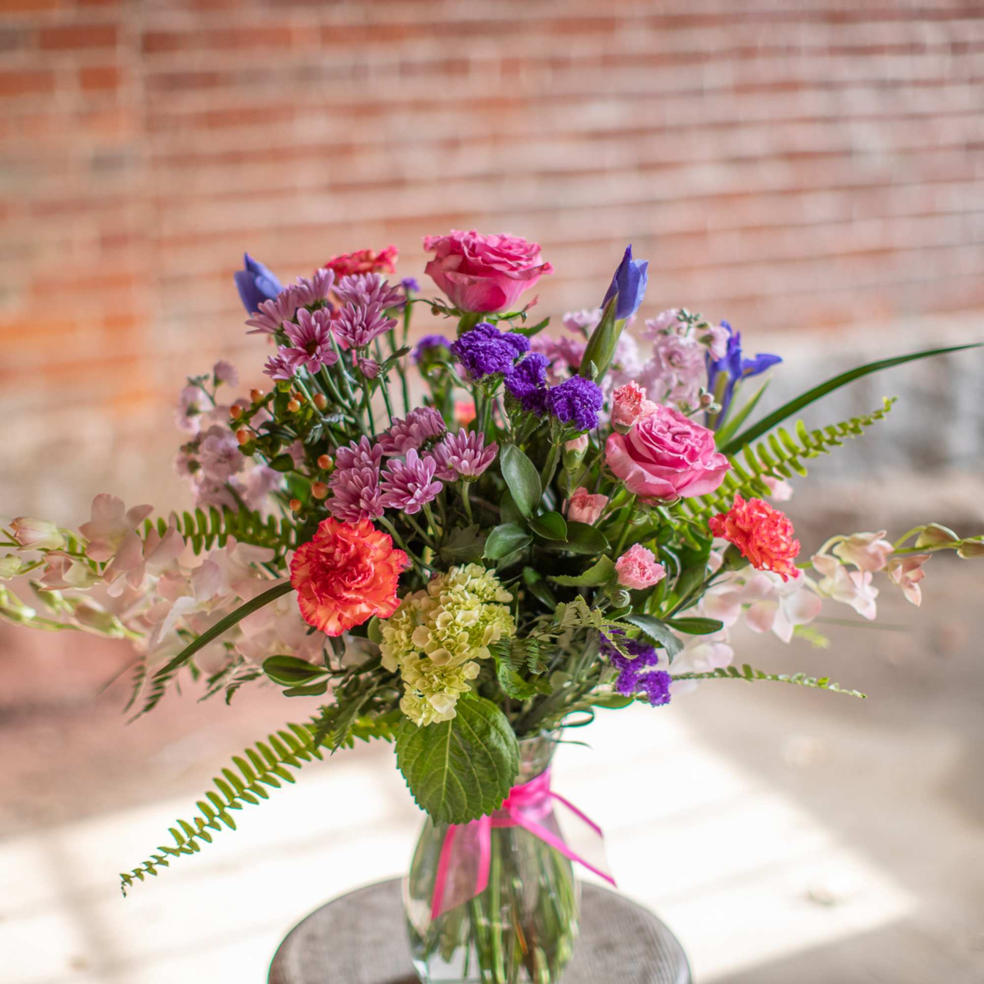 Mixed bouquet of pink, purple, and coral flowers in a glass vase